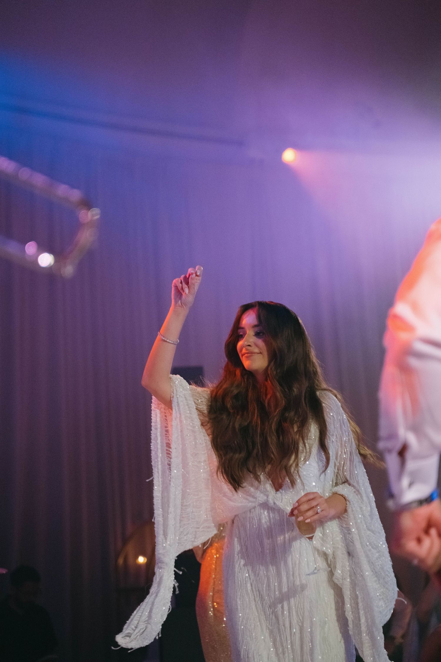 Dance floor celebration with purple lighting and white party attire.