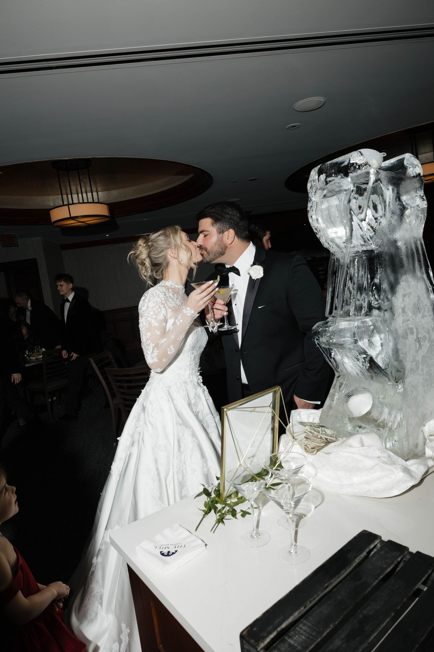 Newlyweds share a toast beside an elegant ice sculpture during their reception celebration.