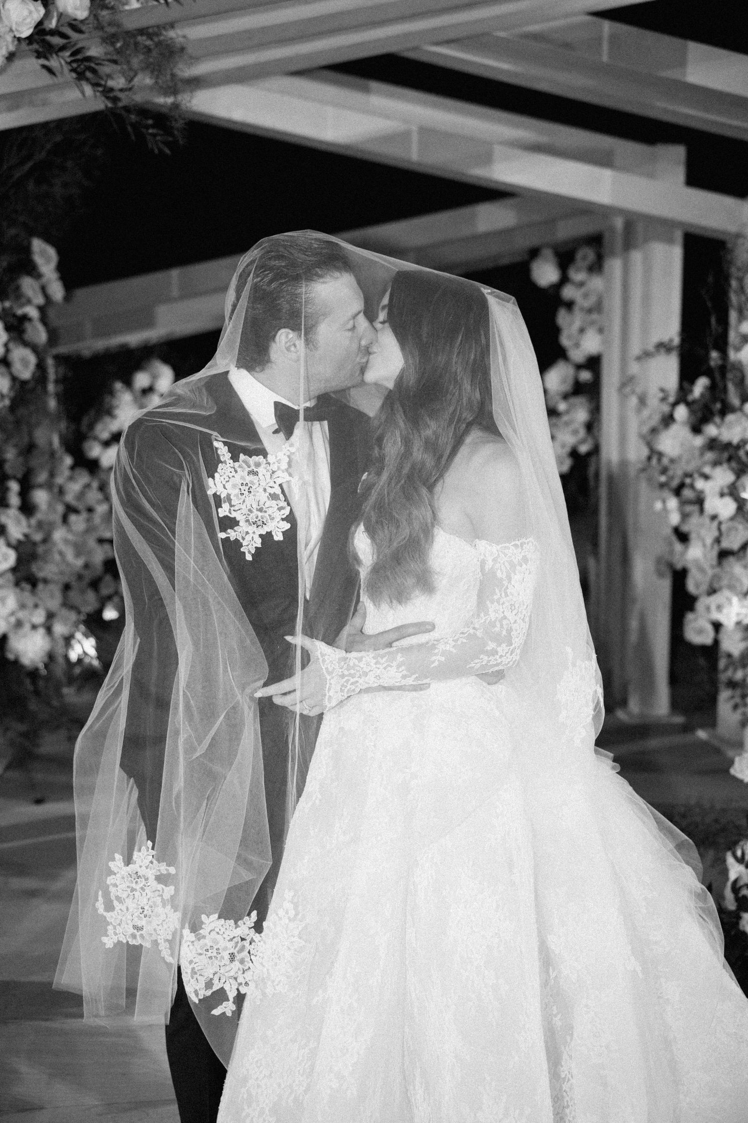 Black and white photograph of an elegant wedding ceremony with delicate lace details.