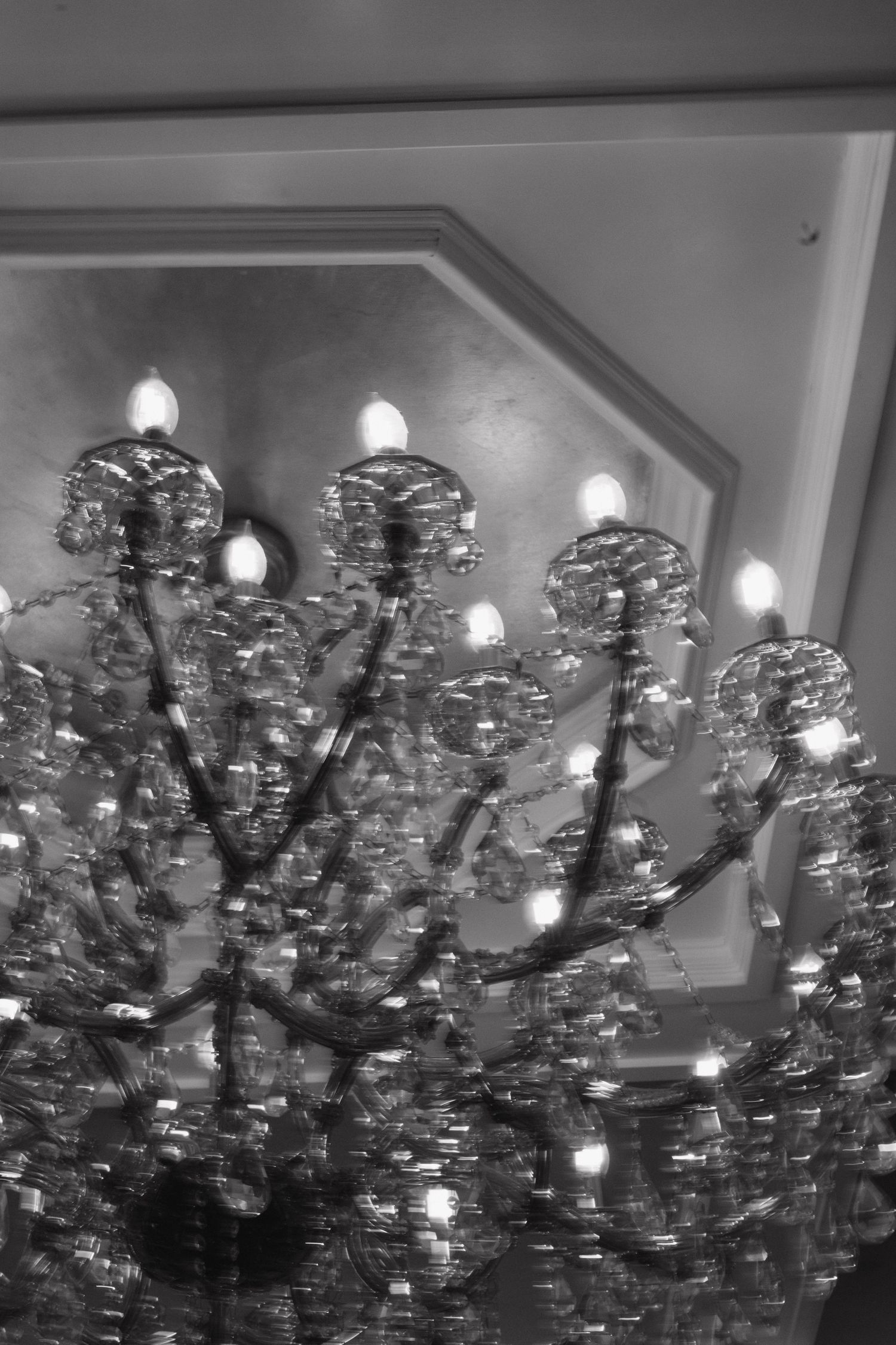Ornate crystal chandelier with multiple tiers photographed from below in a wedding venue.