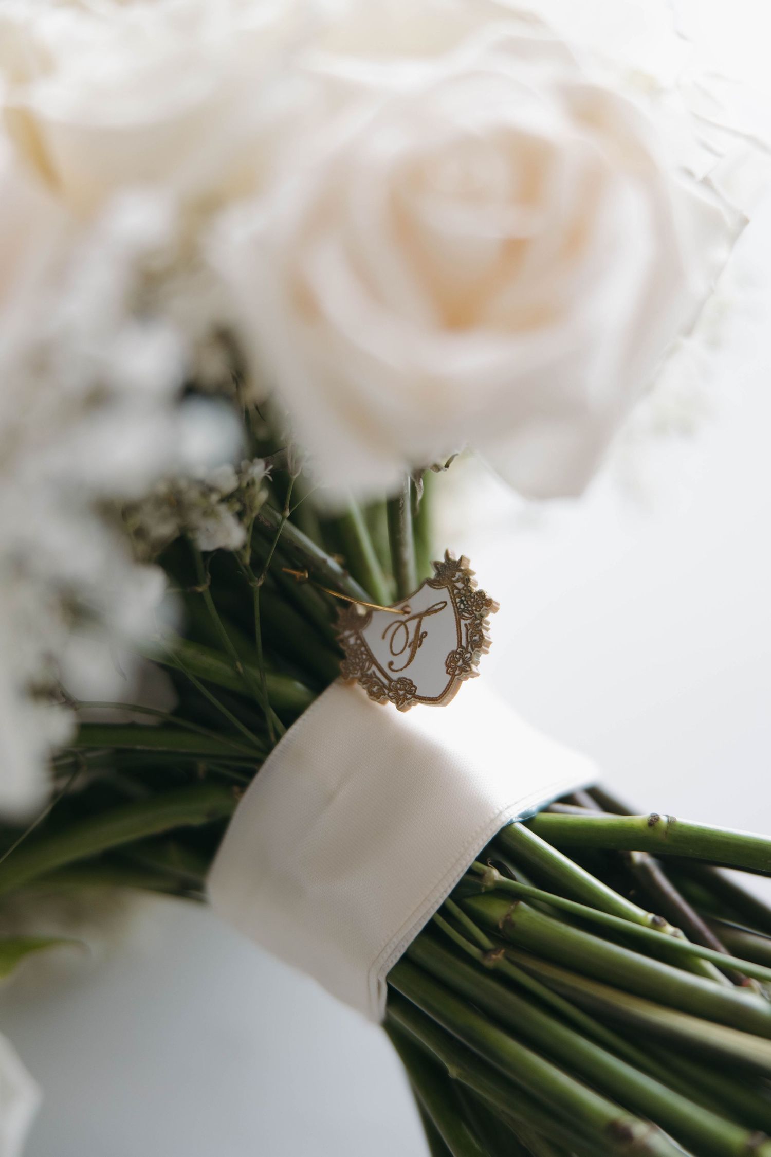 Detail shot of white rose wedding bouquet with decorative wrap and ribbon.