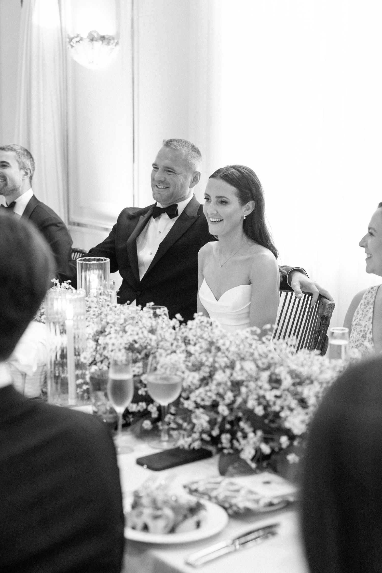 Wedding reception table decorated with delicate baby's breath floral arrangements and white linens.