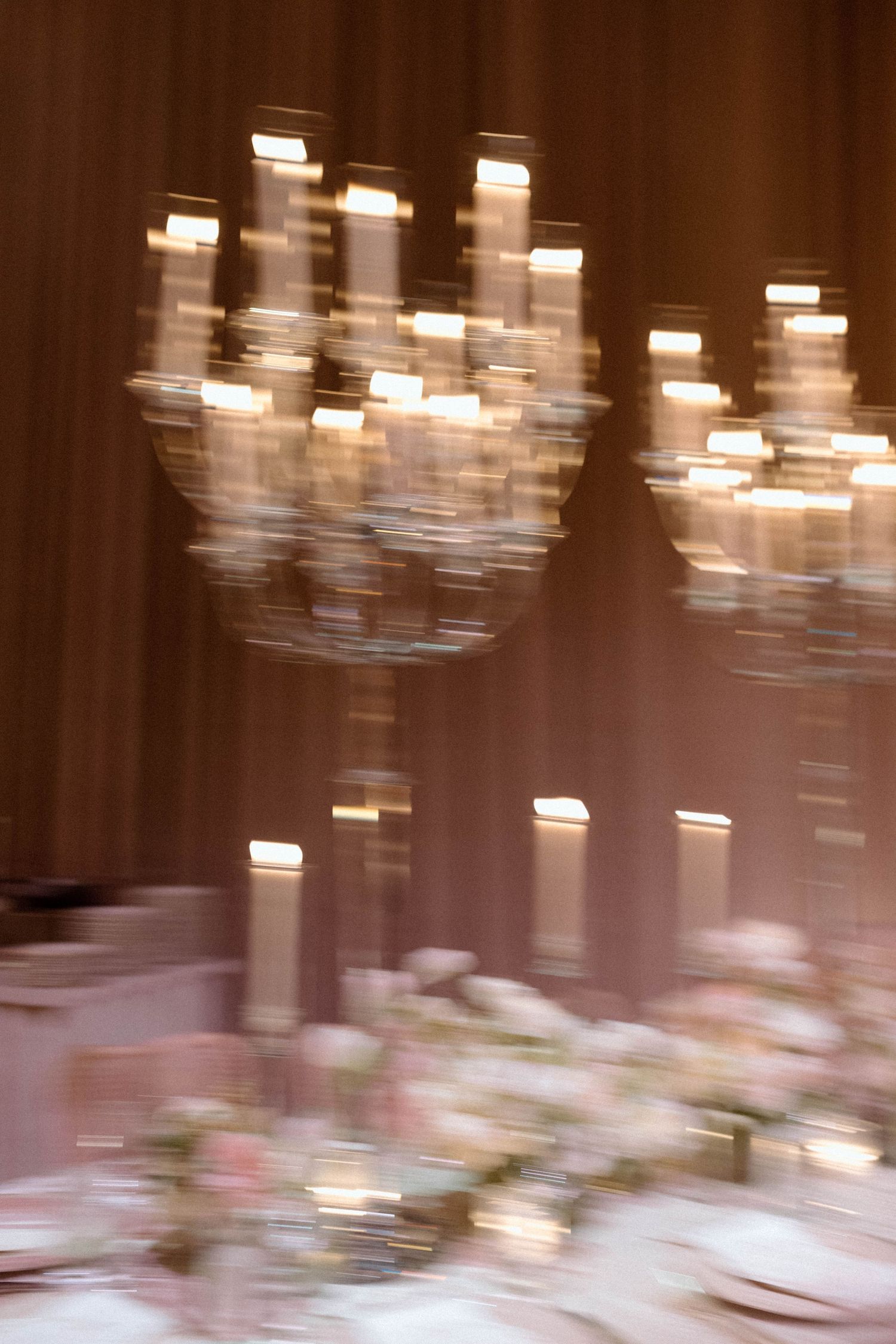 Elegant wedding reception venue with blurred chandelier lights creating a dreamy atmosphere in warm tones.