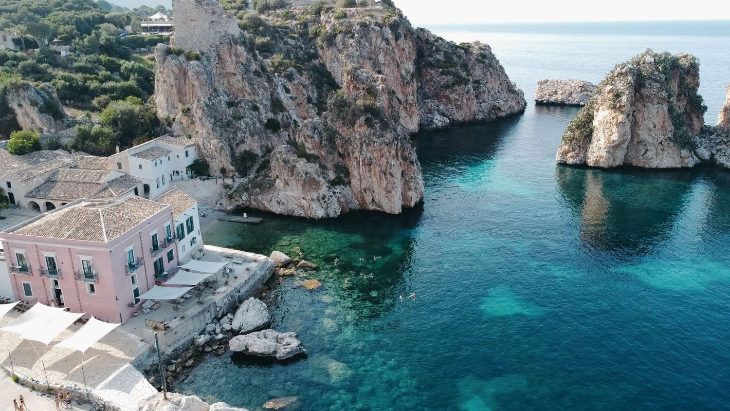 Panoramic view of rocky Mediterranean coastline with turquoise waters and steep cliffs.
