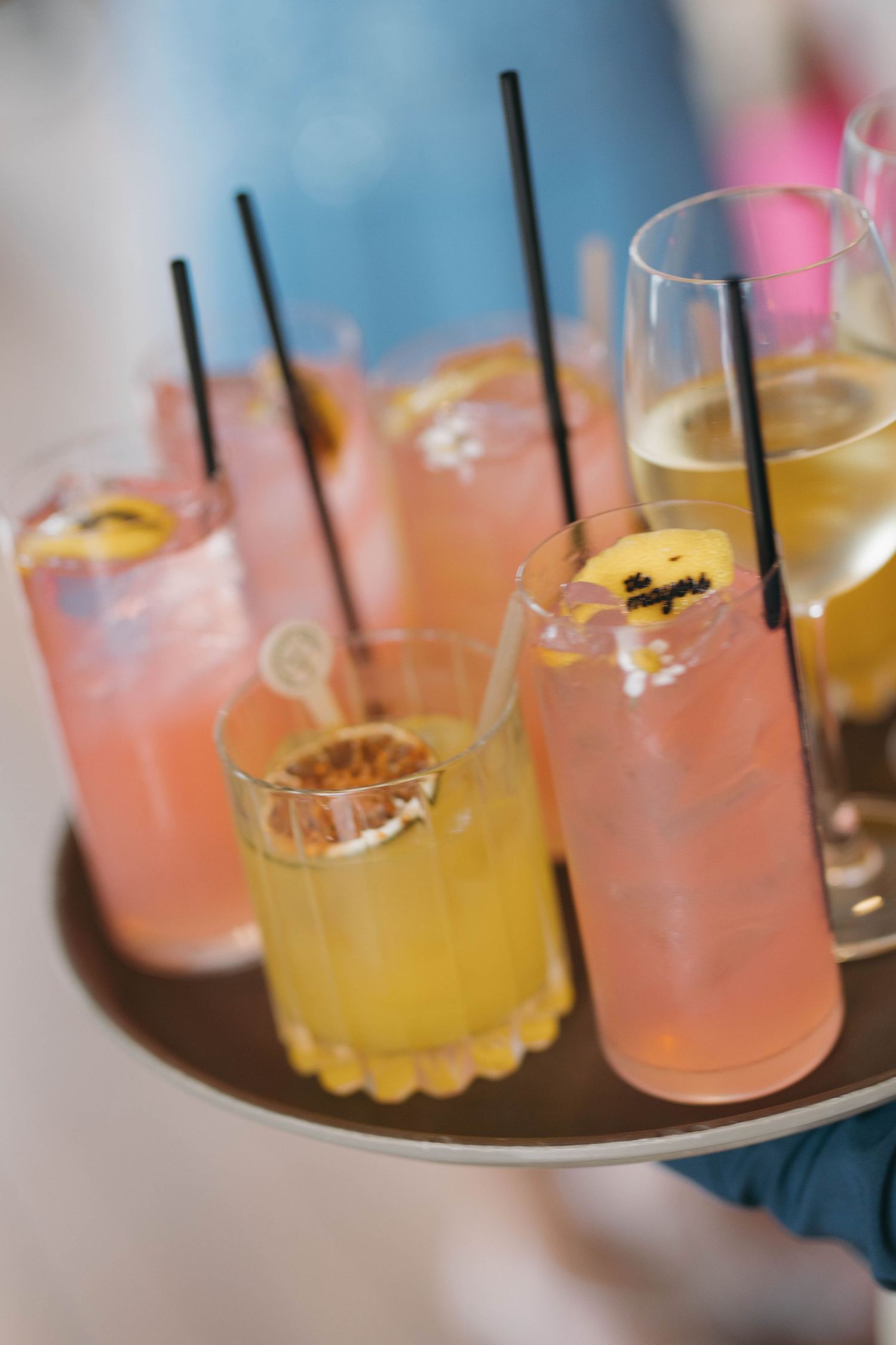 Colorful cocktails with pink and yellow hues served in elegant glassware at a wedding reception.