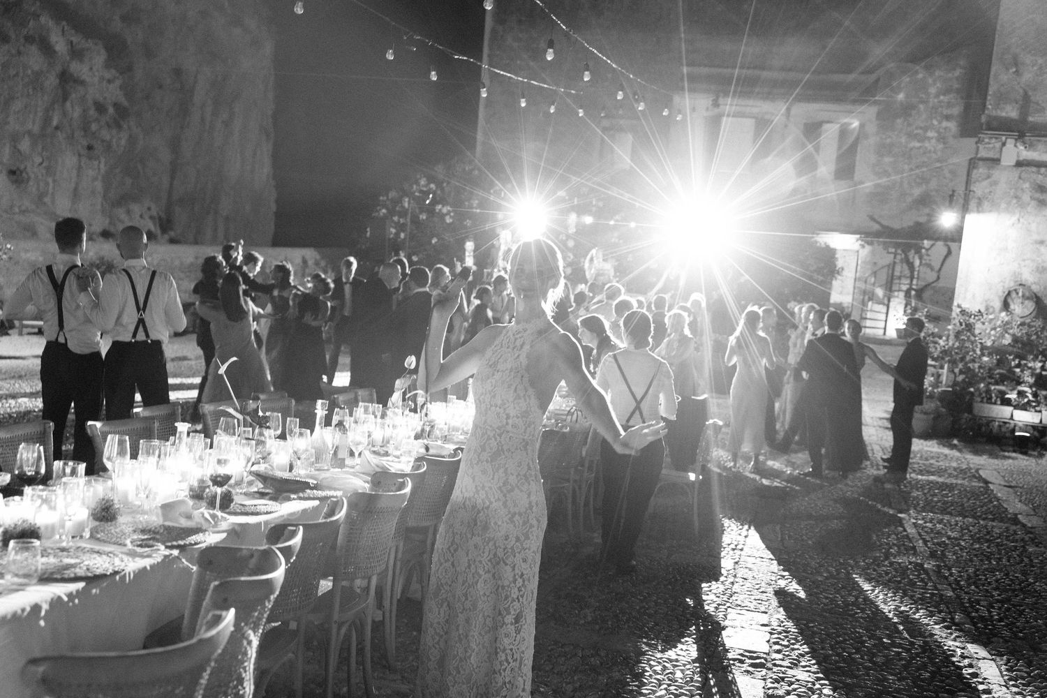 Dramatic backlit scene of an evening celebration with bright lights and elegant table settings.