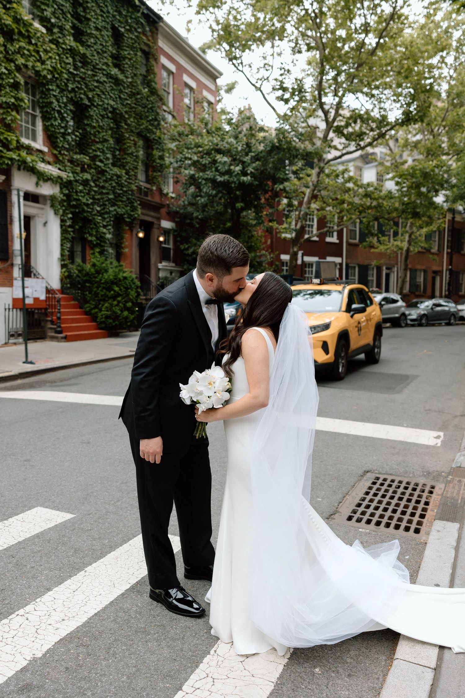 Wedding couple poses playfully on a cobblestone street in an urban neighborhood.