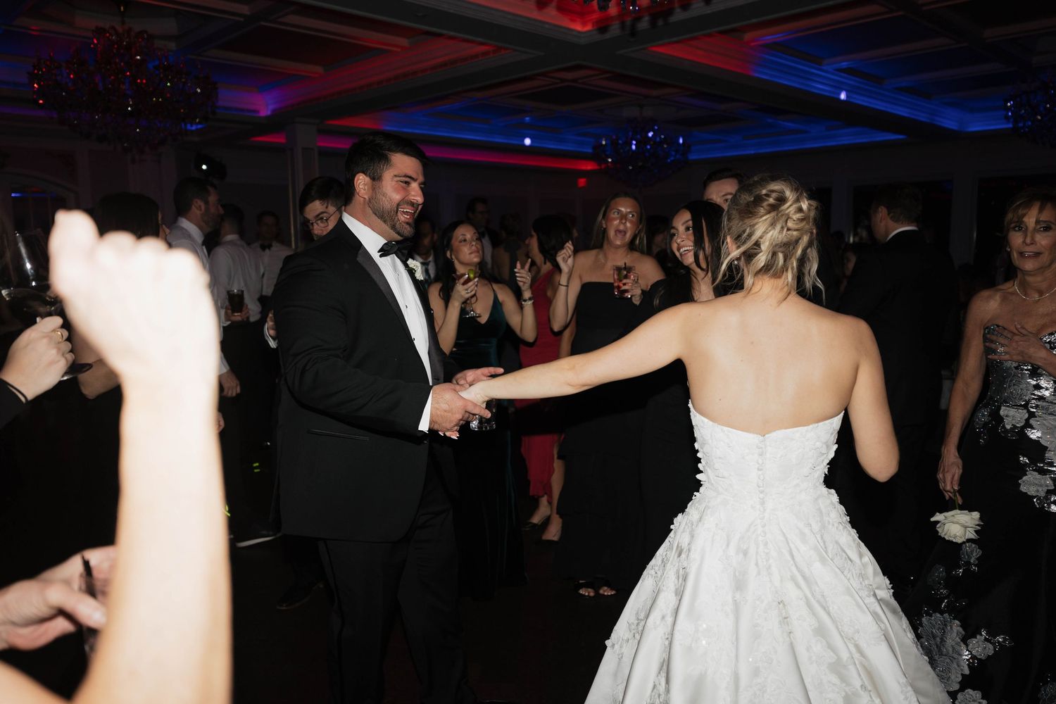 Wedding reception dance floor with guests celebrating in dark ambient lighting.
