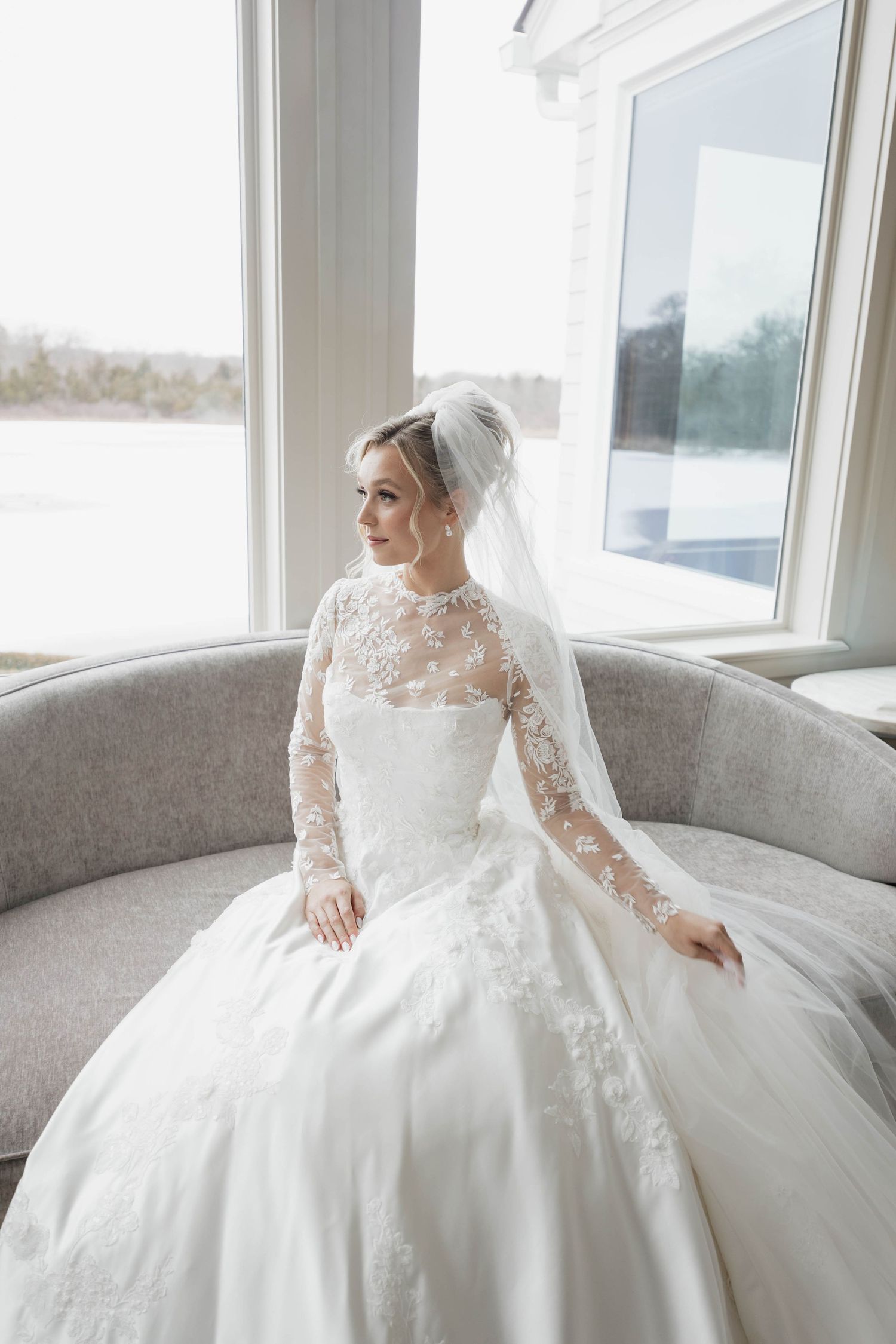Elegant bridal portrait featuring classic ballgown silhouette against grey sofa.