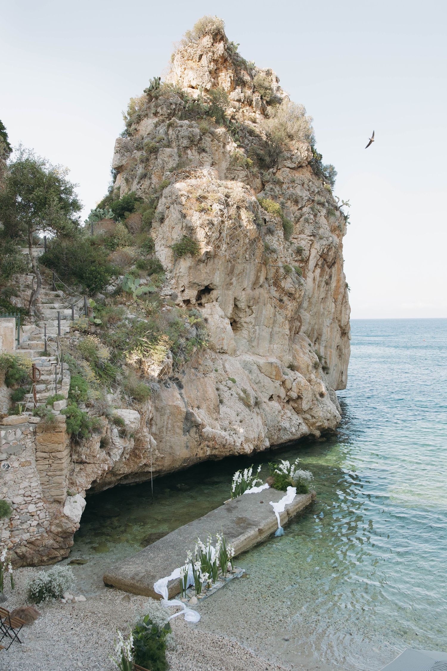 Scenic Mediterranean beach wedding venue with cliffside views and rustic seating arrangements.