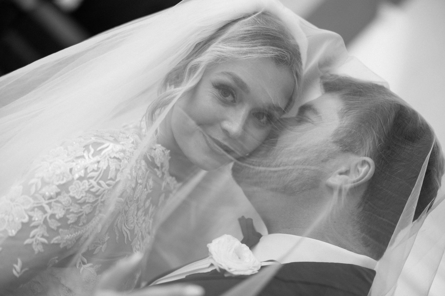 Romantic black and white portrait of couple under bridal veil.
