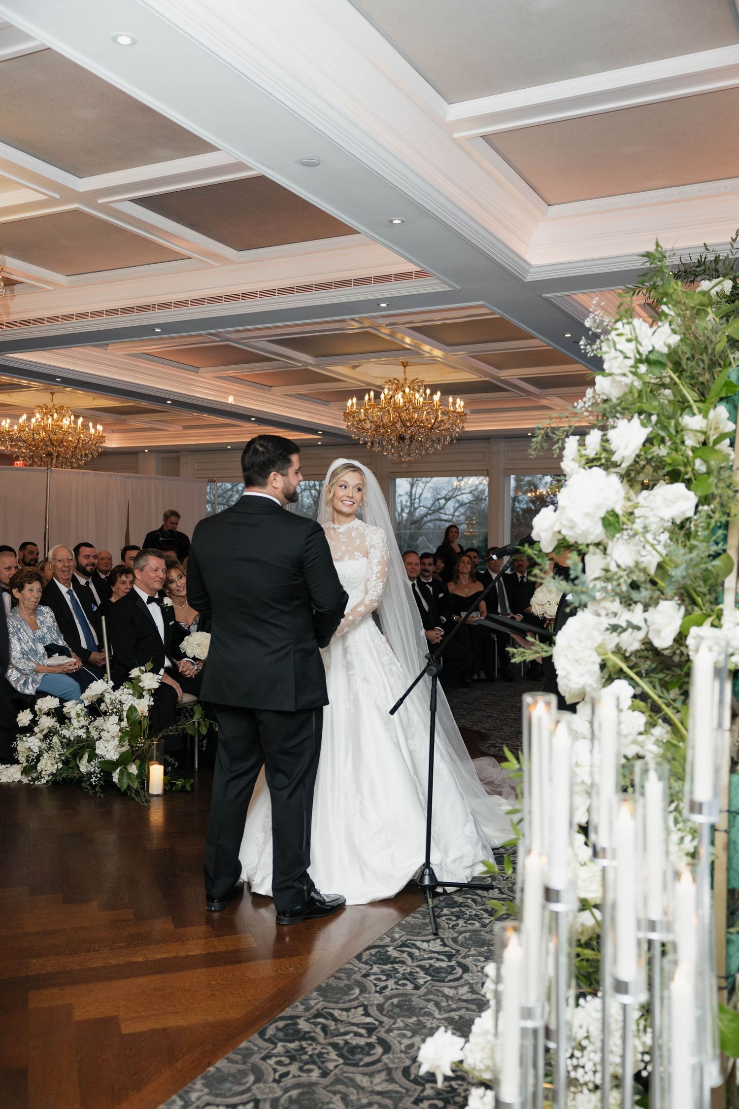 Elegant wedding ceremony with coffered ceiling and floral-lined aisle.