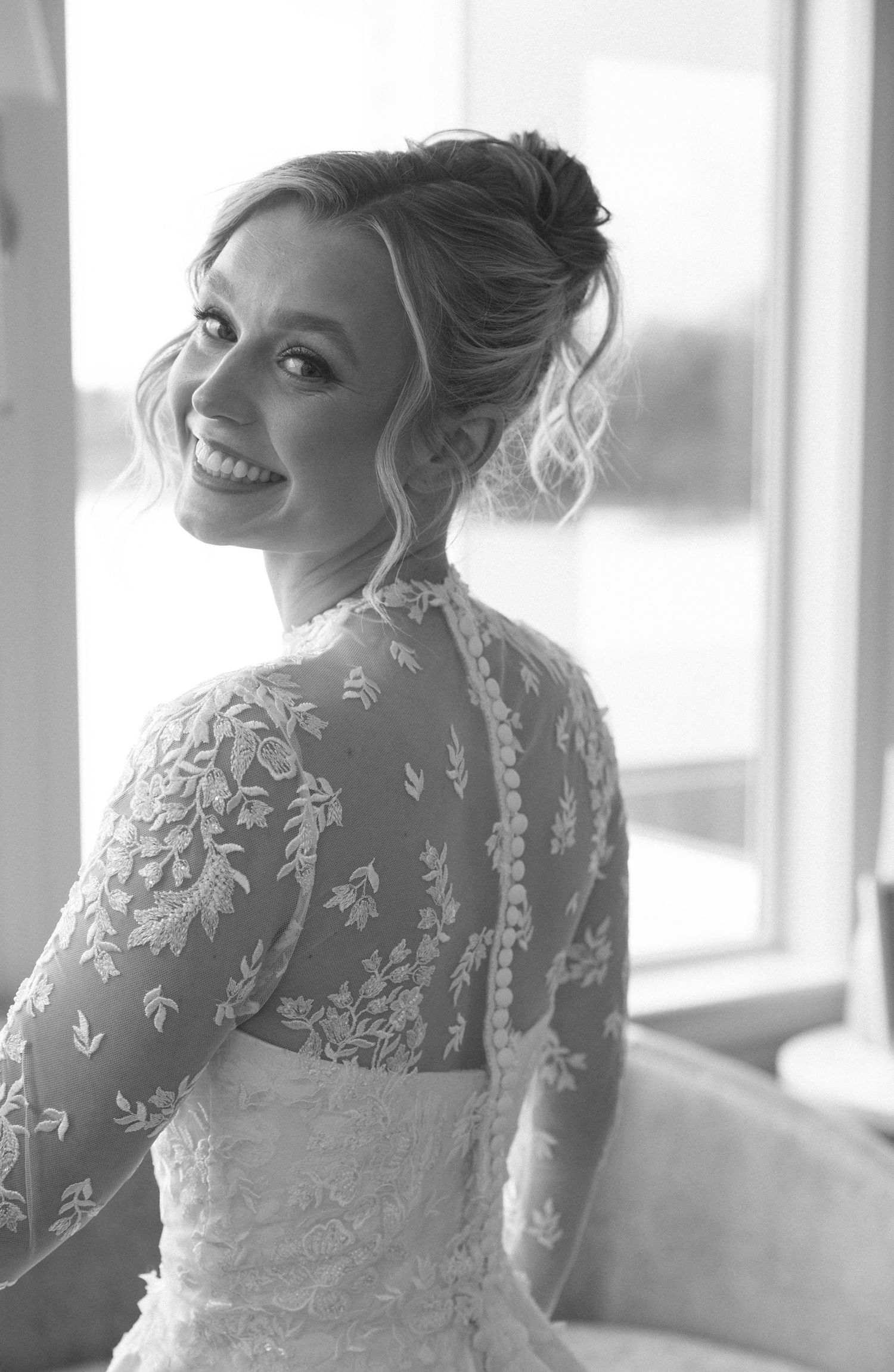 Elegant lace wedding dress with delicate floral details in window light.