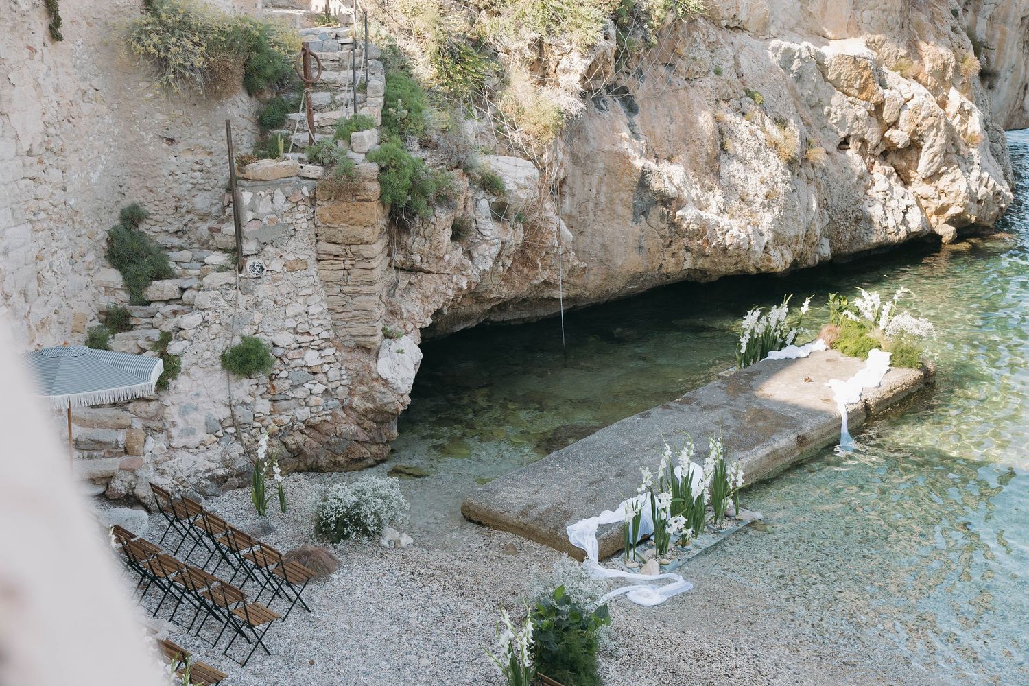 Stone archway overlooking a secluded beach cove with crystal blue Mediterranean waters.
