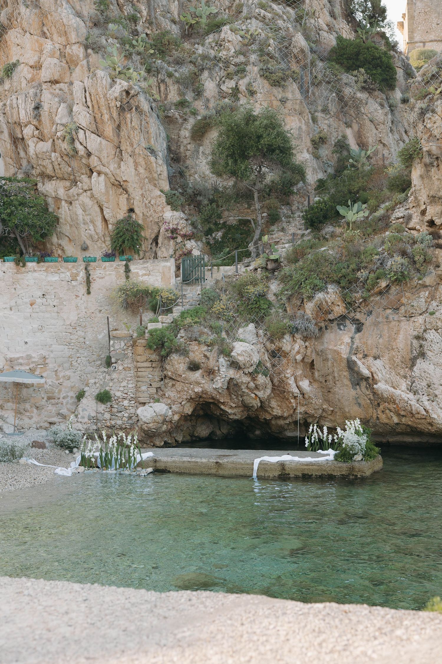 Scenic Mediterranean cove with white buildings nestled into rocky cliffs above turquoise waters.