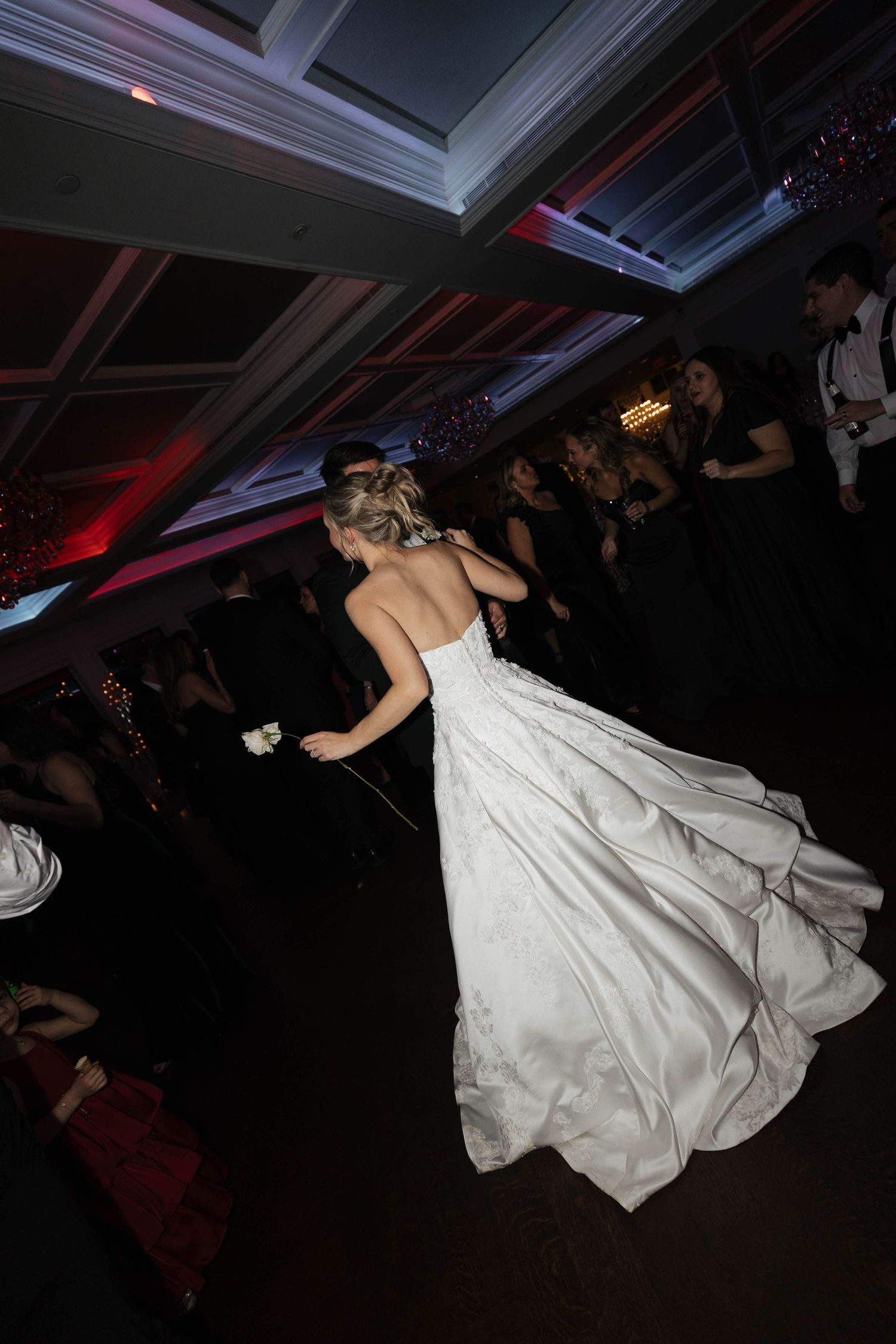 Dramatic low-light shot of flowing white wedding dress during reception dance.