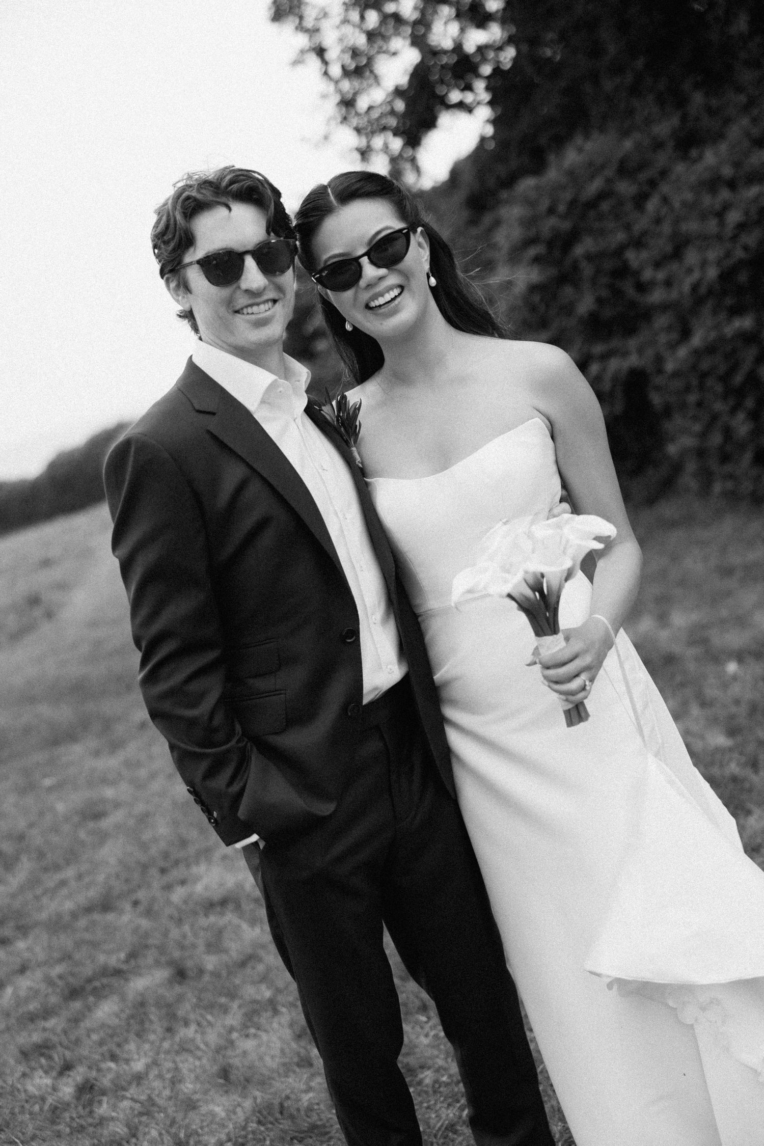 Black and white photos of a couple sharing playful moments outdoors on their wedding day.
