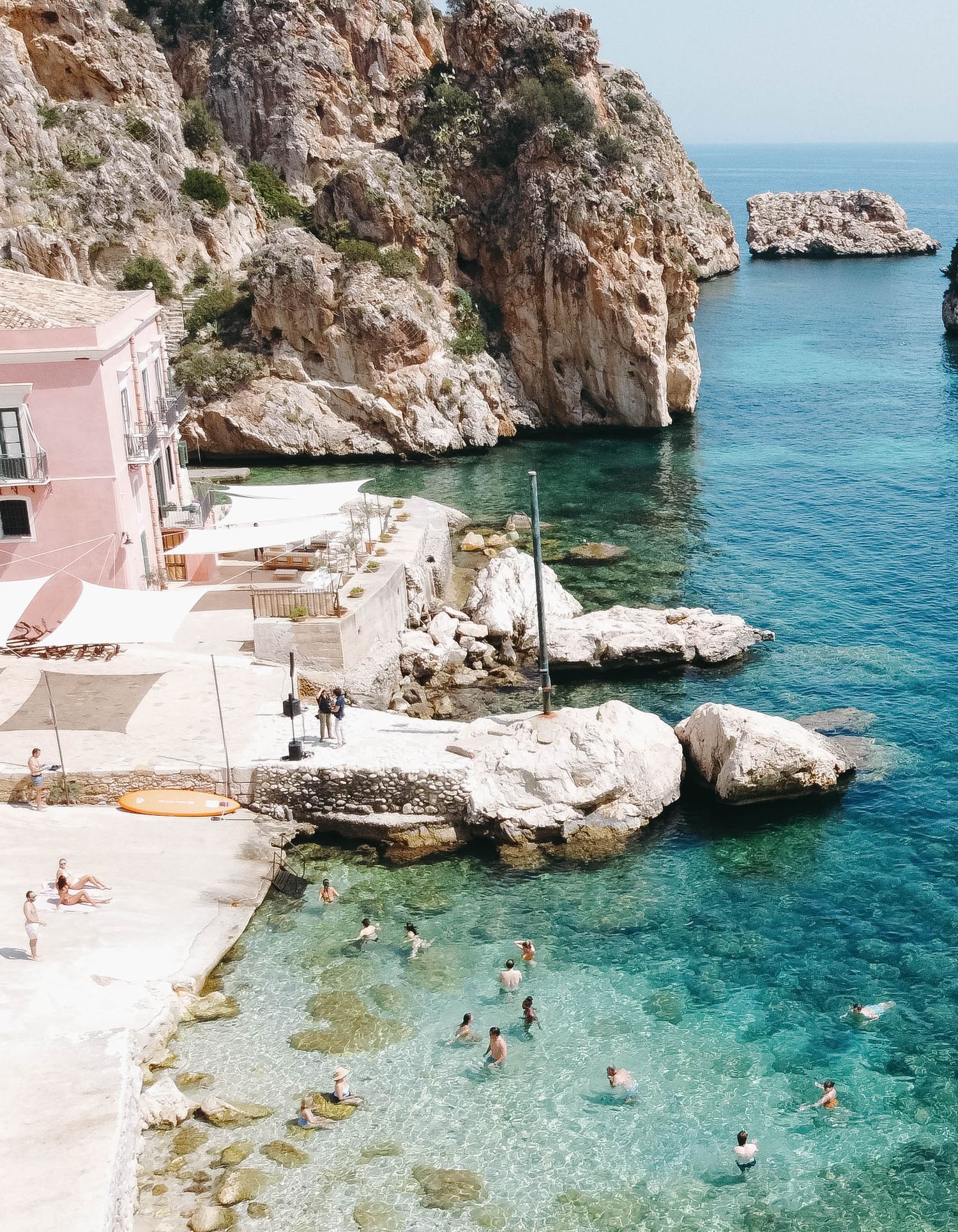 Beachgoers enjoying crystal clear waters in a secluded cove surrounded by limestone cliffs.