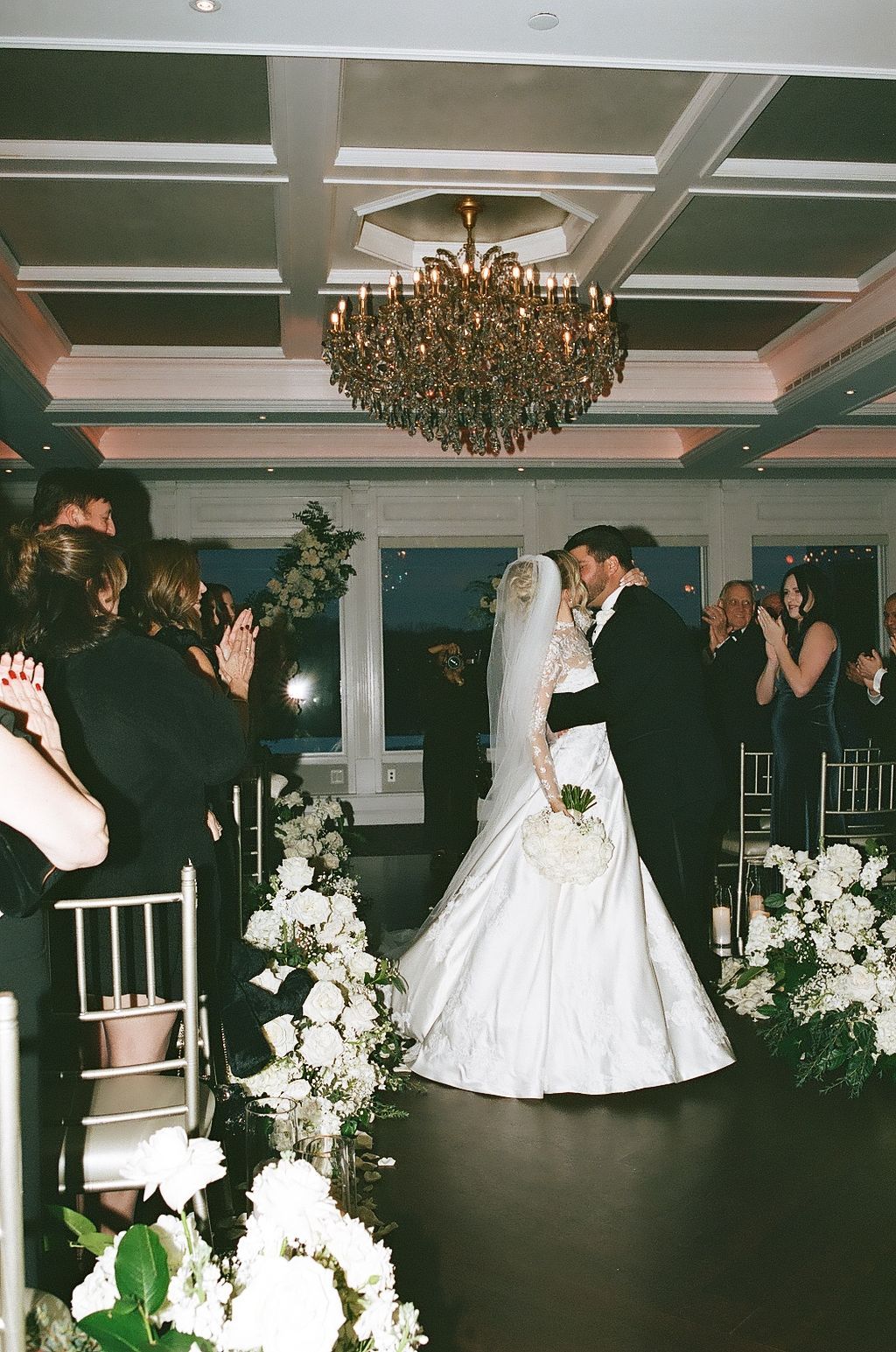 Wedding reception dance sequence showing couples dancing together in an elegant ballroom with white floral decorations.