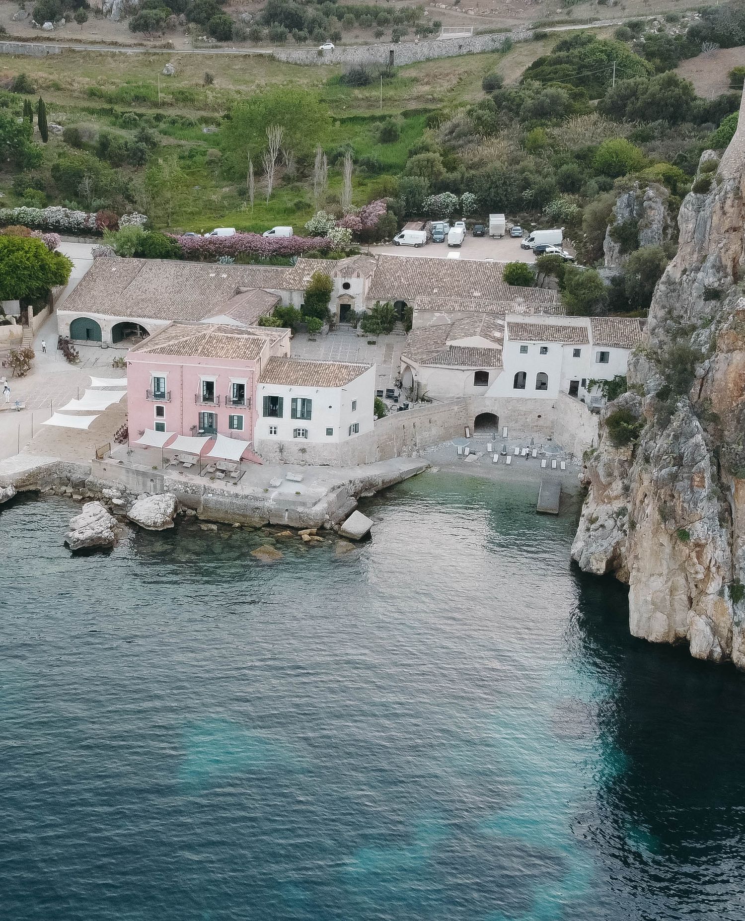 Coastal village with traditional buildings and a small harbor tucked between dramatic limestone cliffs.