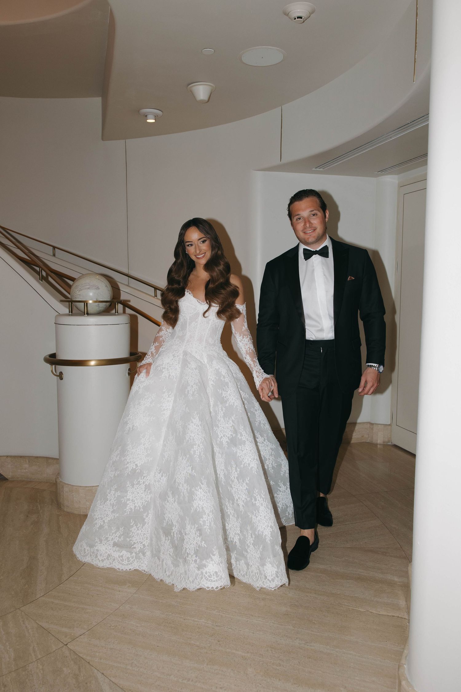 Wedding couple photographed in a modern white hallway with curved architectural details.