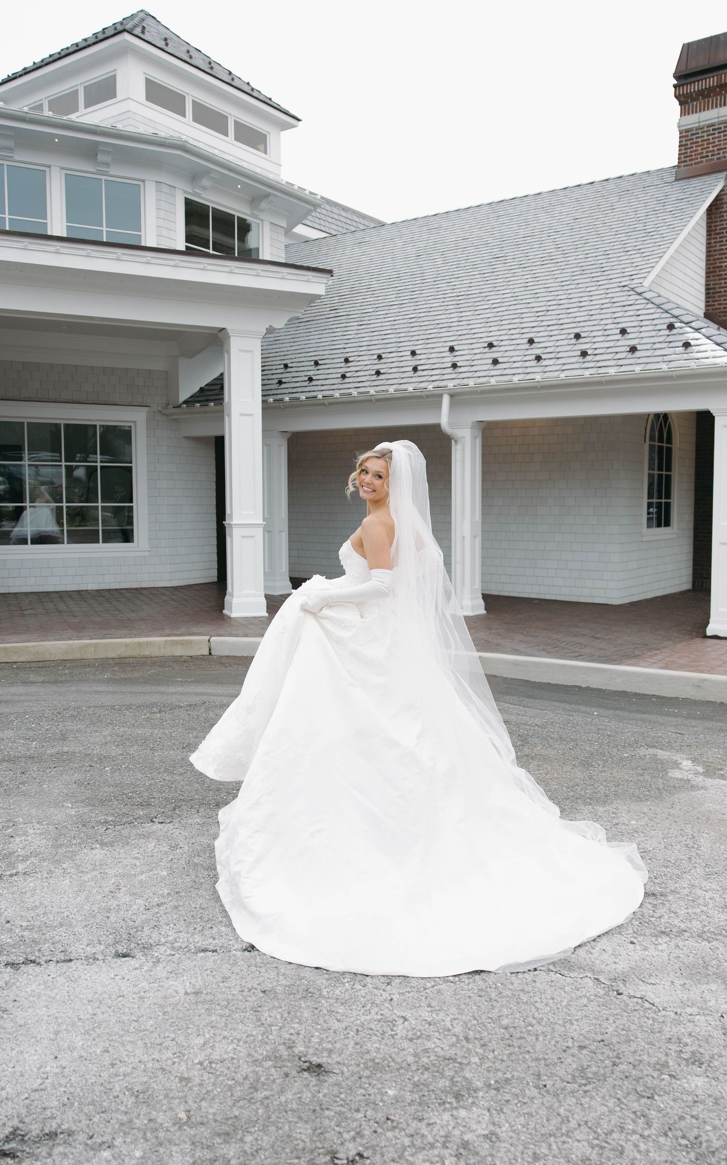 A flowing white wedding dress creates dramatic silhouette against modern white architecture.