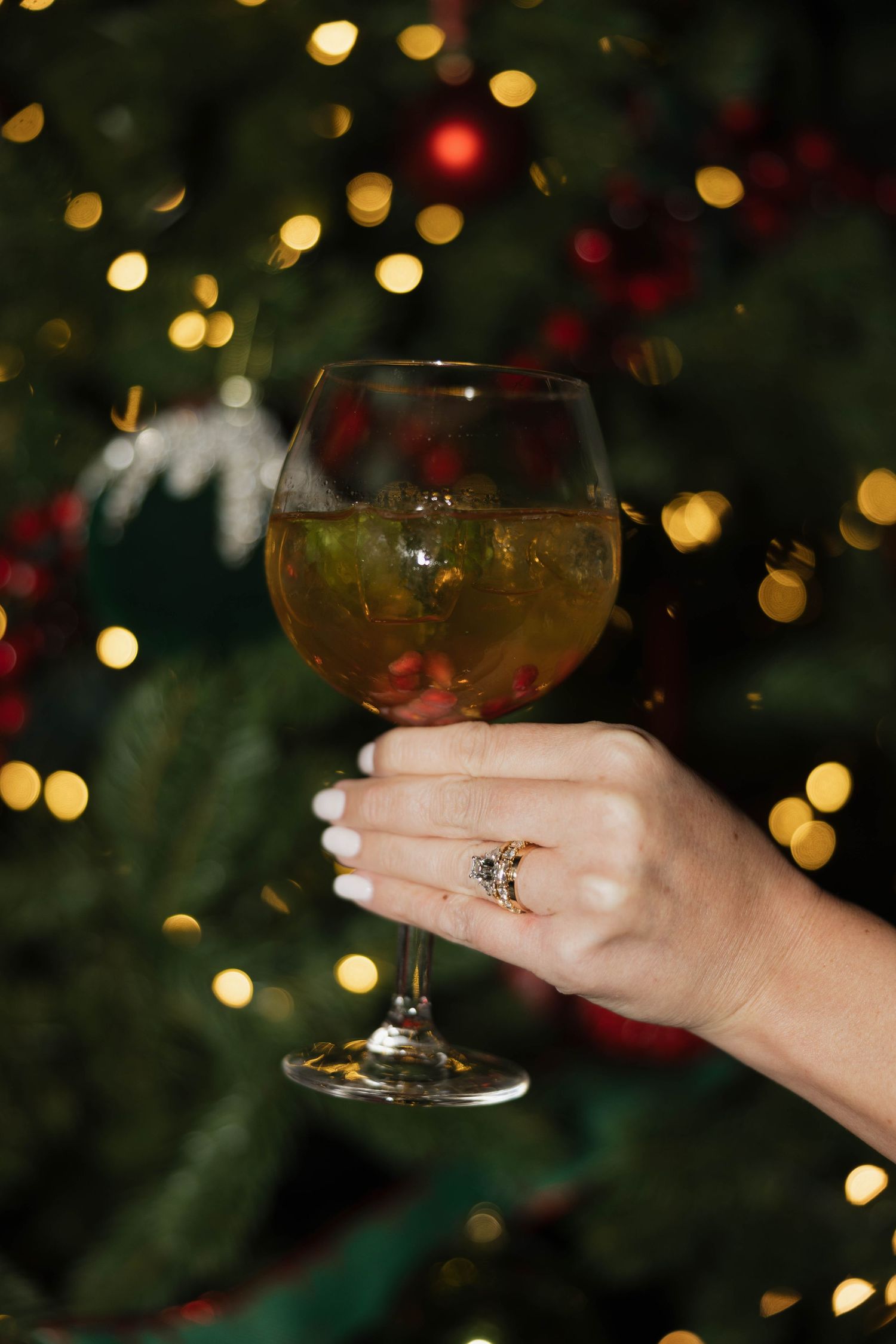 Champagne glass held against bokeh lights from Christmas decorations.