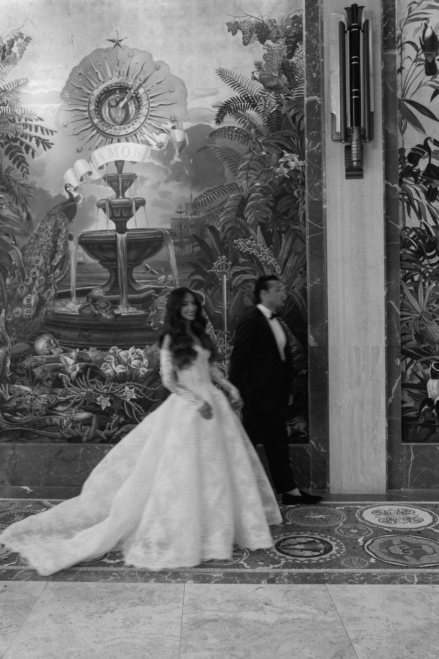 Black and white wedding photos against a decorative wall with tropical murals and elegant decor.