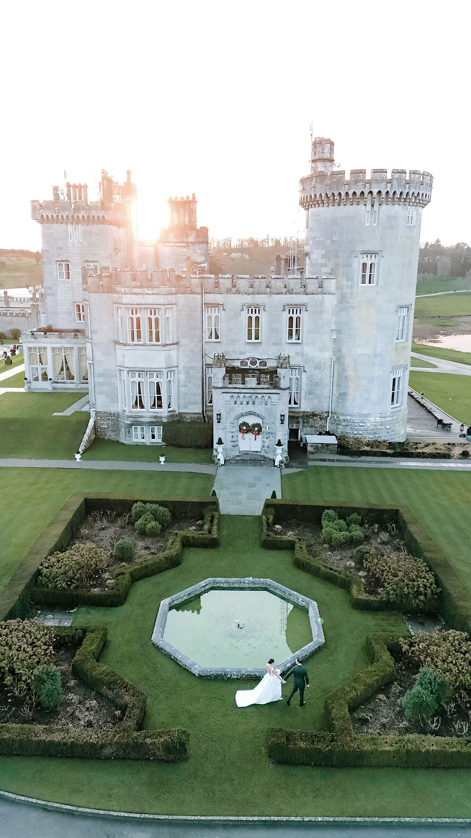 Aerial view of a grand castle with geometric gardens and an octagonal pool feature.