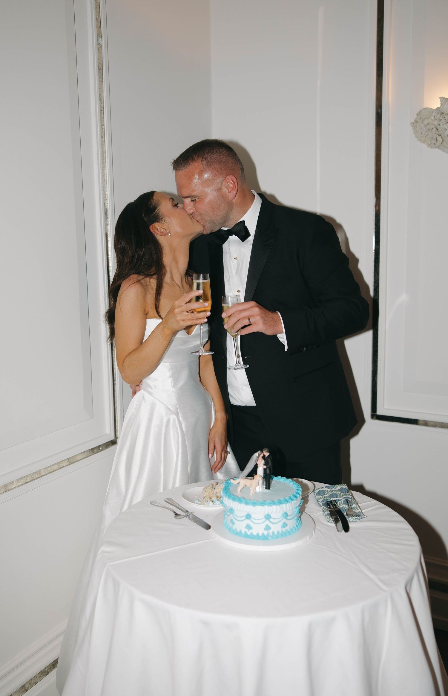 Newlyweds sharing champagne and a moment together by their wedding cake.