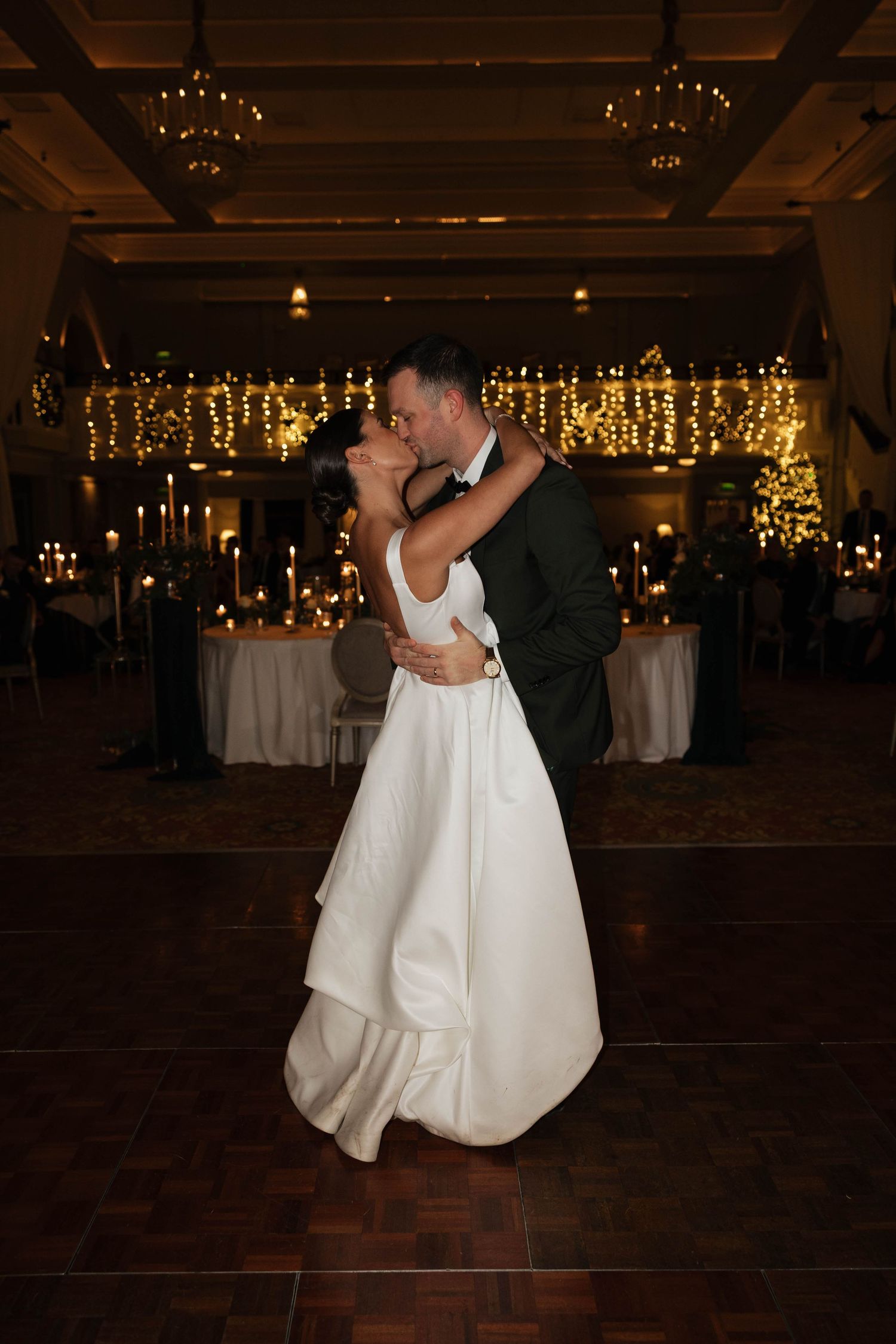 A romantic first dance sequence on a dark wooden dance floor with twinkling lights above.