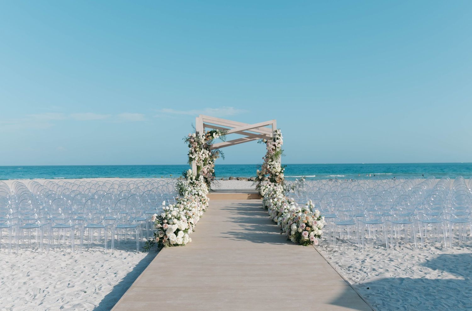 Minimalist beach wedding setup with decorated arch and ocean view.
