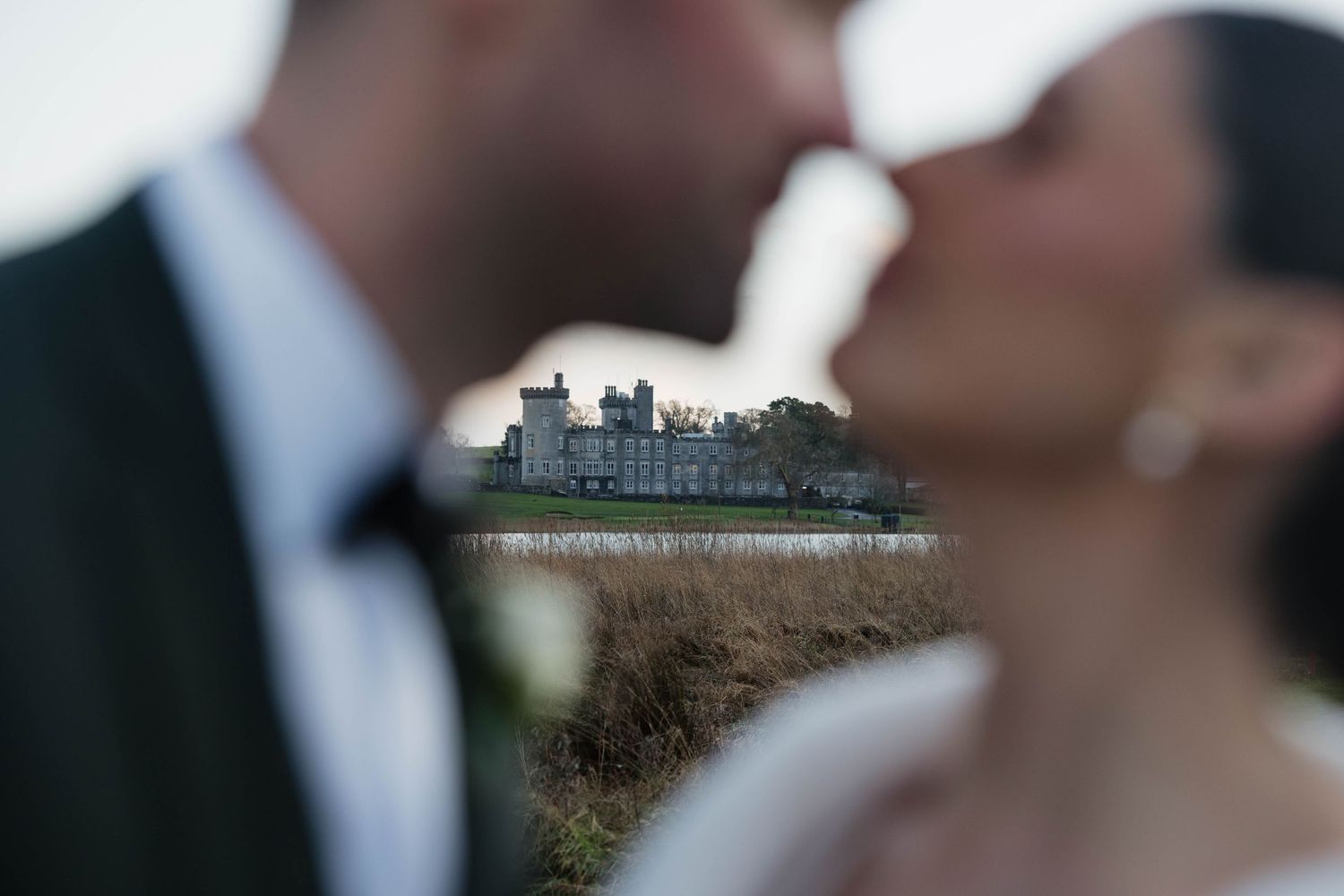 Wedding couple poses with historic castle architecture visible in the distance.