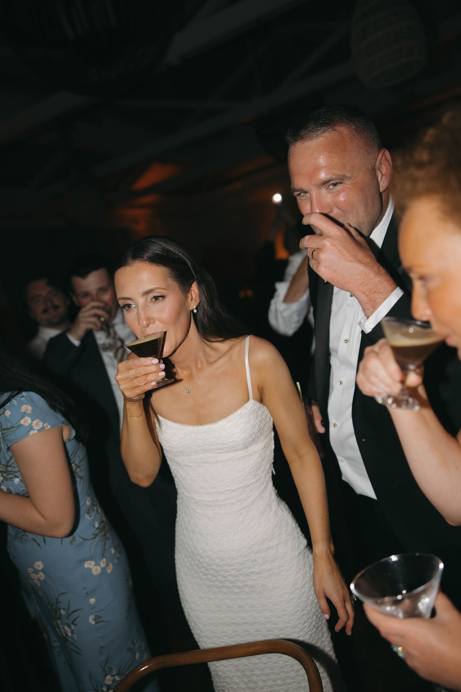 People in formal attire dancing and celebrating at a dimly lit reception.