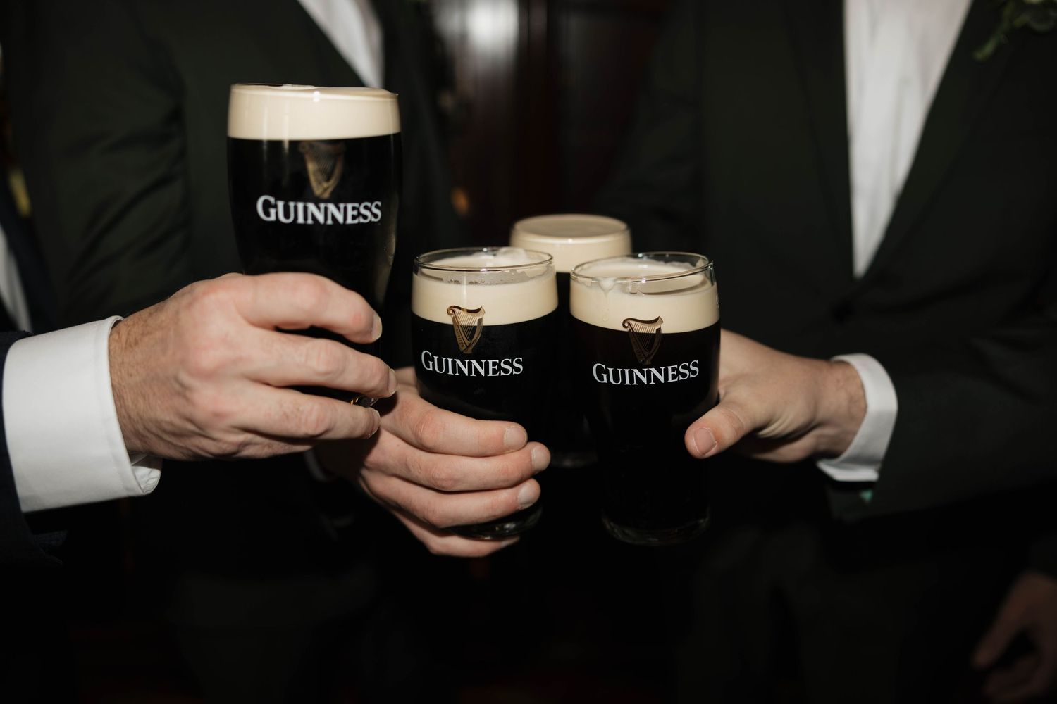 Close-up of Guinness pints being held during wedding celebration.