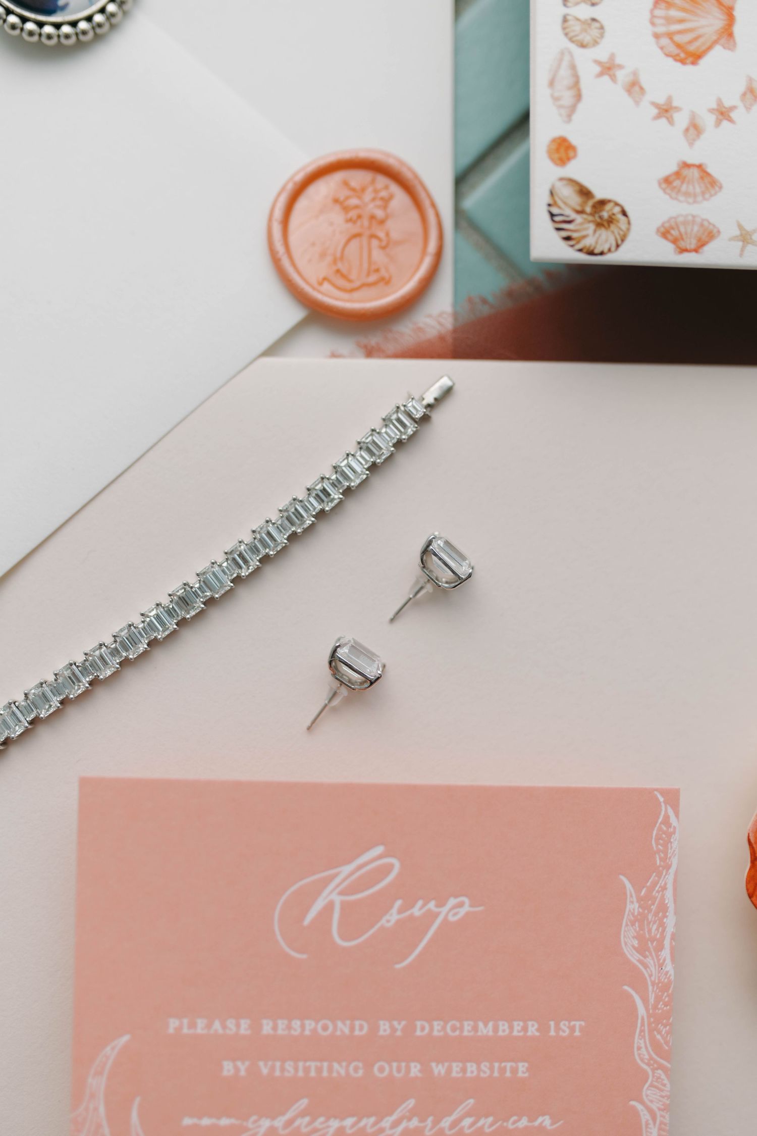 Wedding RSVP card in coral pink with crystal bracelet and earrings.