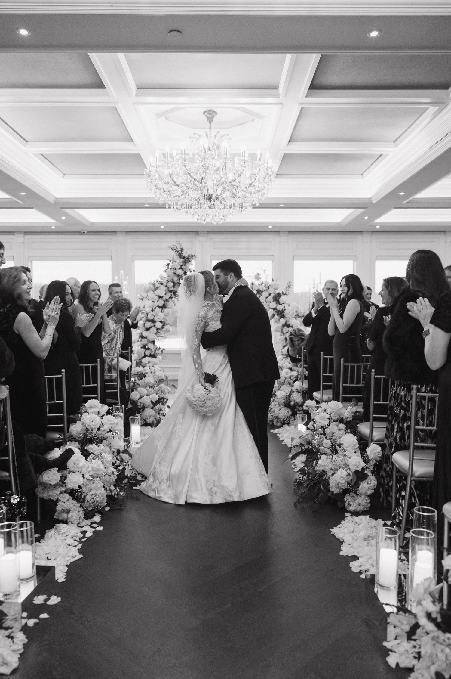 Black and white wedding photo with guests clapping during ceremony.