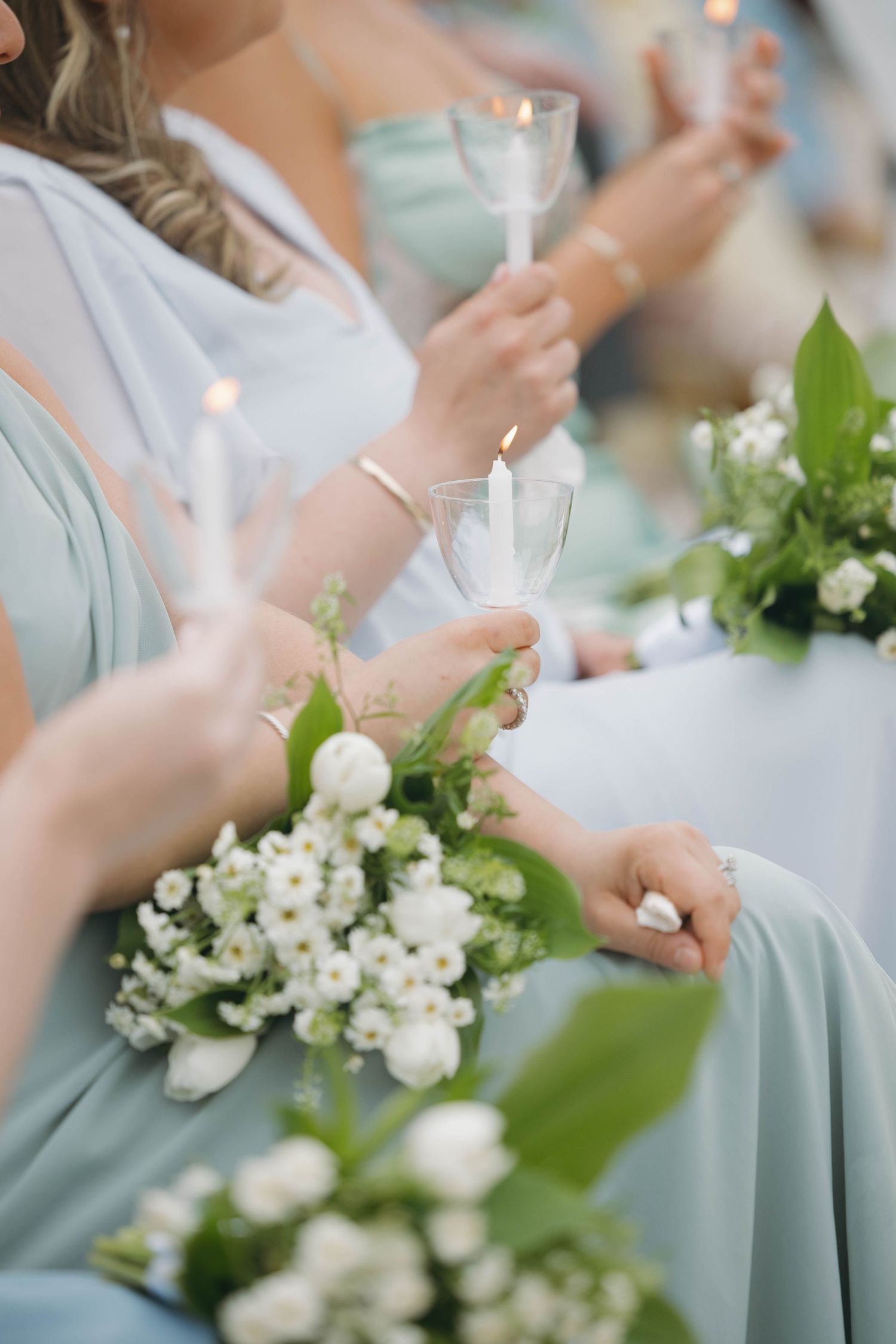 Bridesmaids in pale blue dresses hold champagne glasses with white floral bouquets.