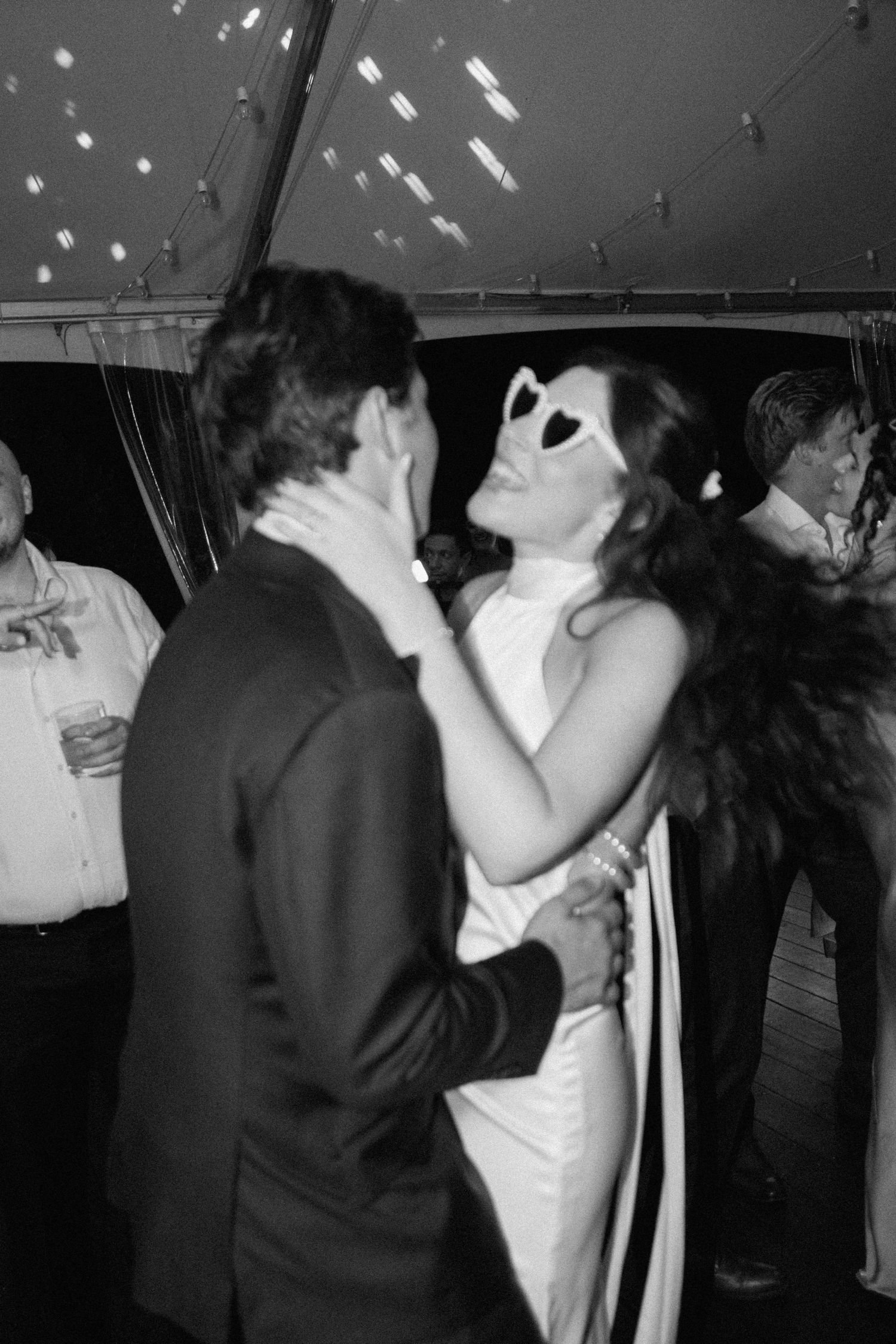 Black and white photo of couples dancing at a dimly lit reception.