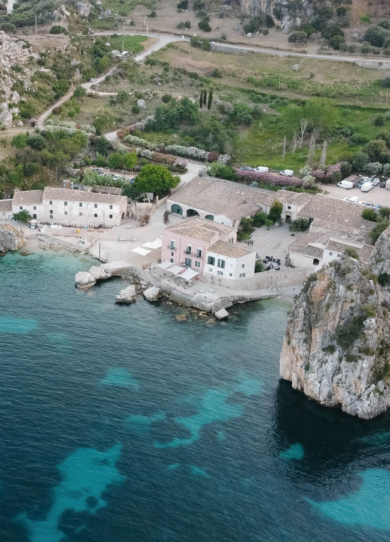 Aerial view showing the contrast between rugged terrain and turquoise waters at a coastal settlement.