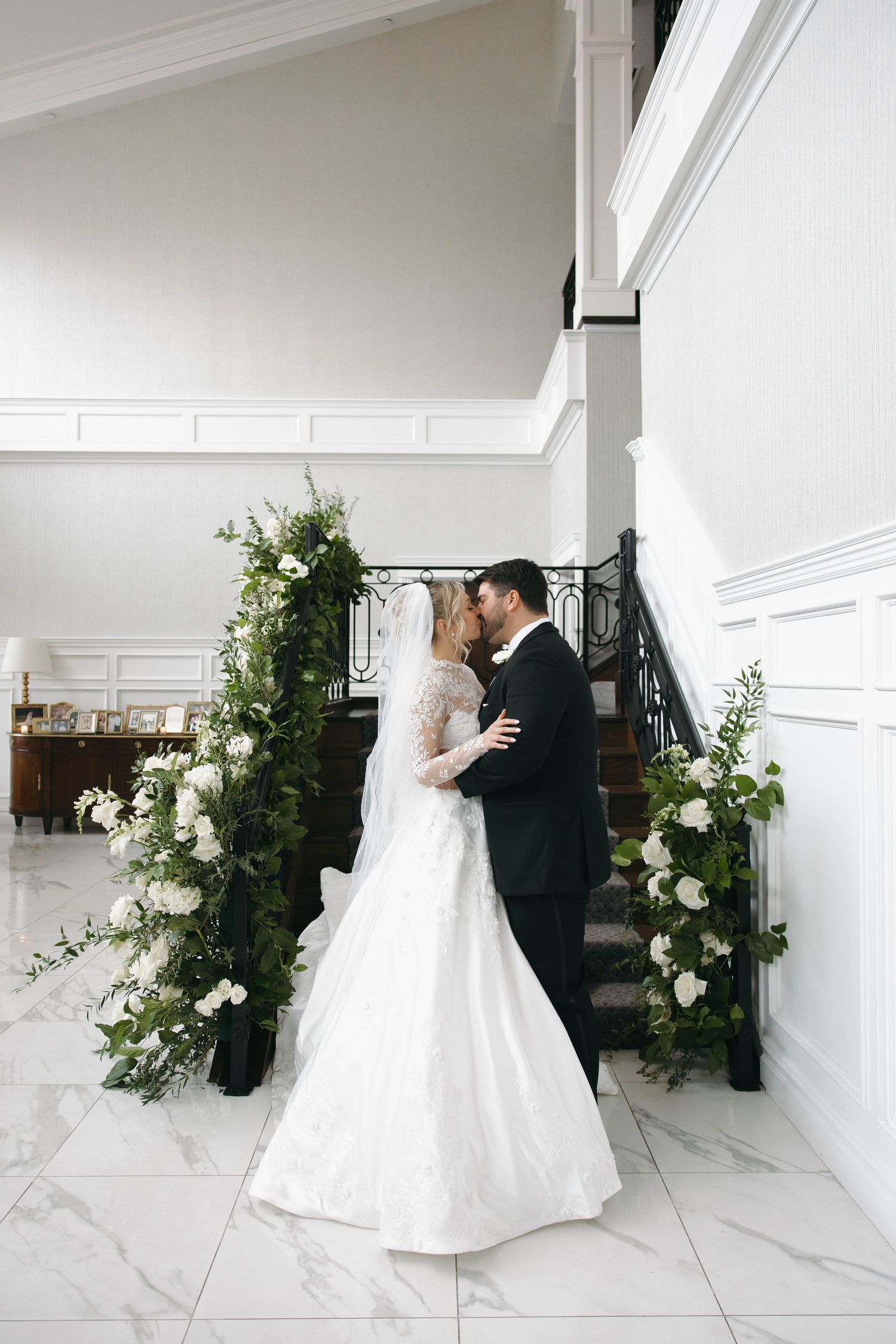 Elegant wedding photos with white floral arrangements against modern white walls.