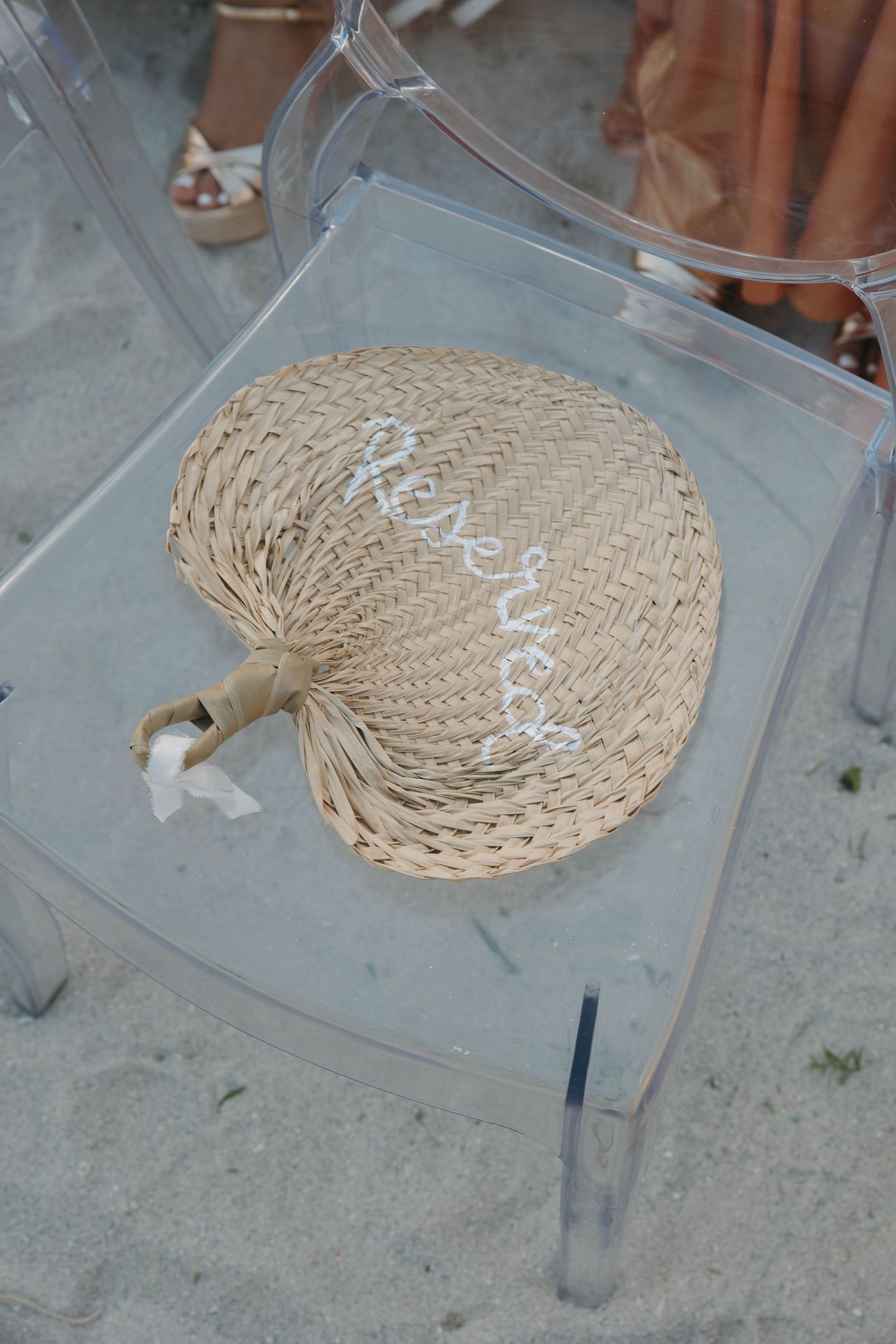 A woven straw fan or decorative piece displayed on a clear acrylic surface.