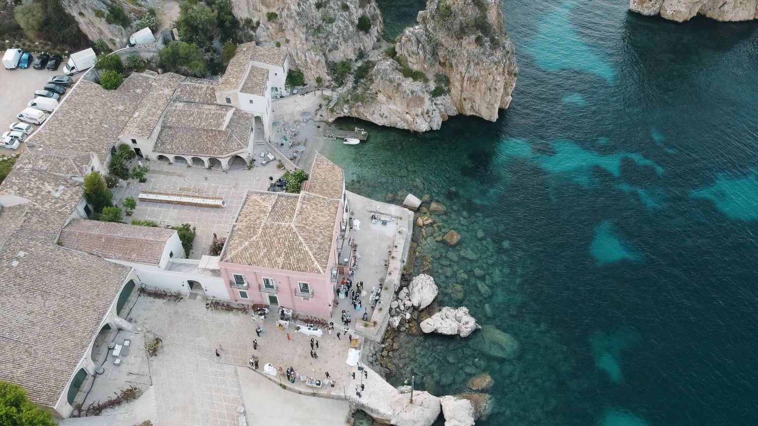 Panoramic coastal landscape showing traditional buildings nestled against turquoise Mediterranean waters.