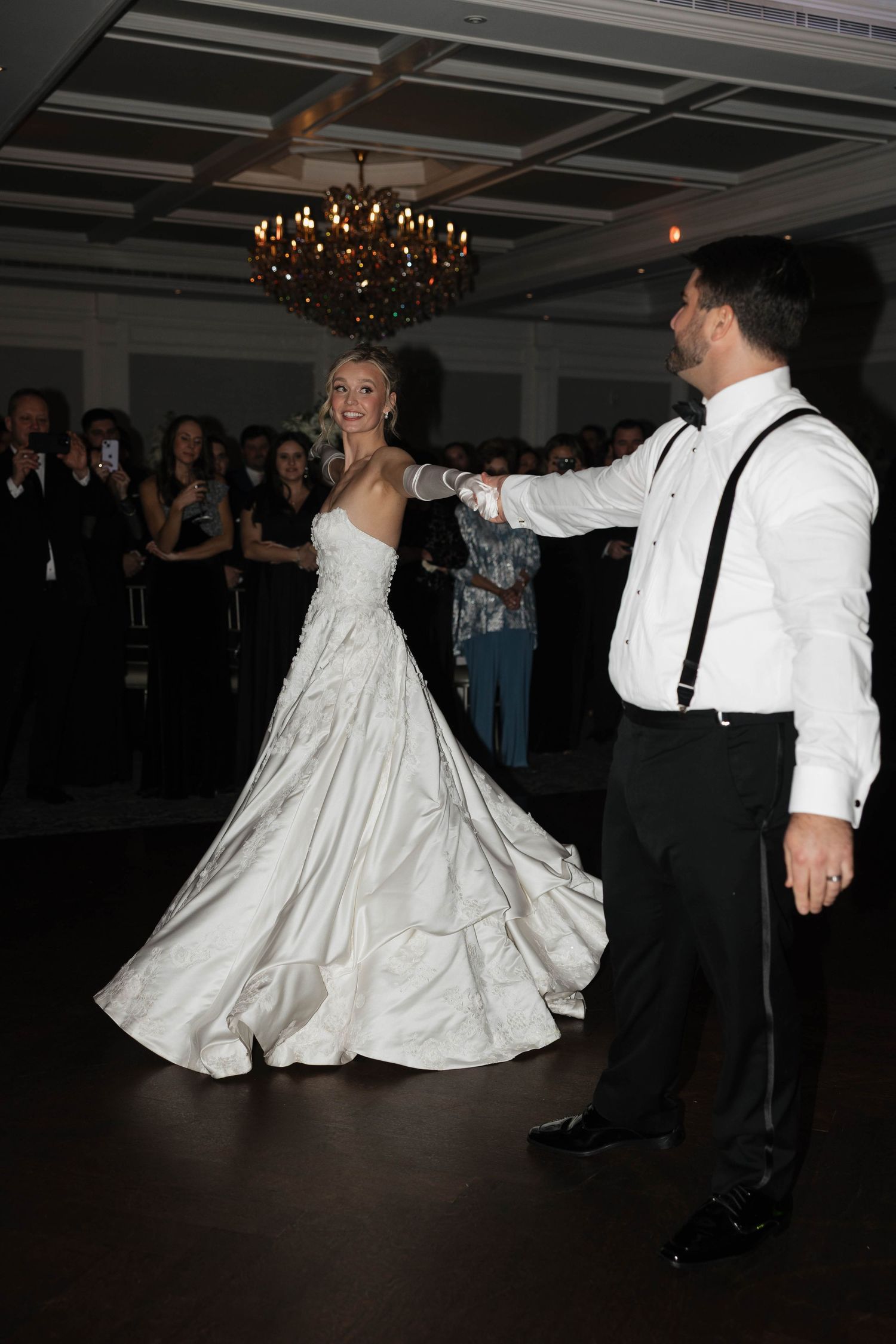 Wedding couple performing first dance while guests watch in elegant reception venue.