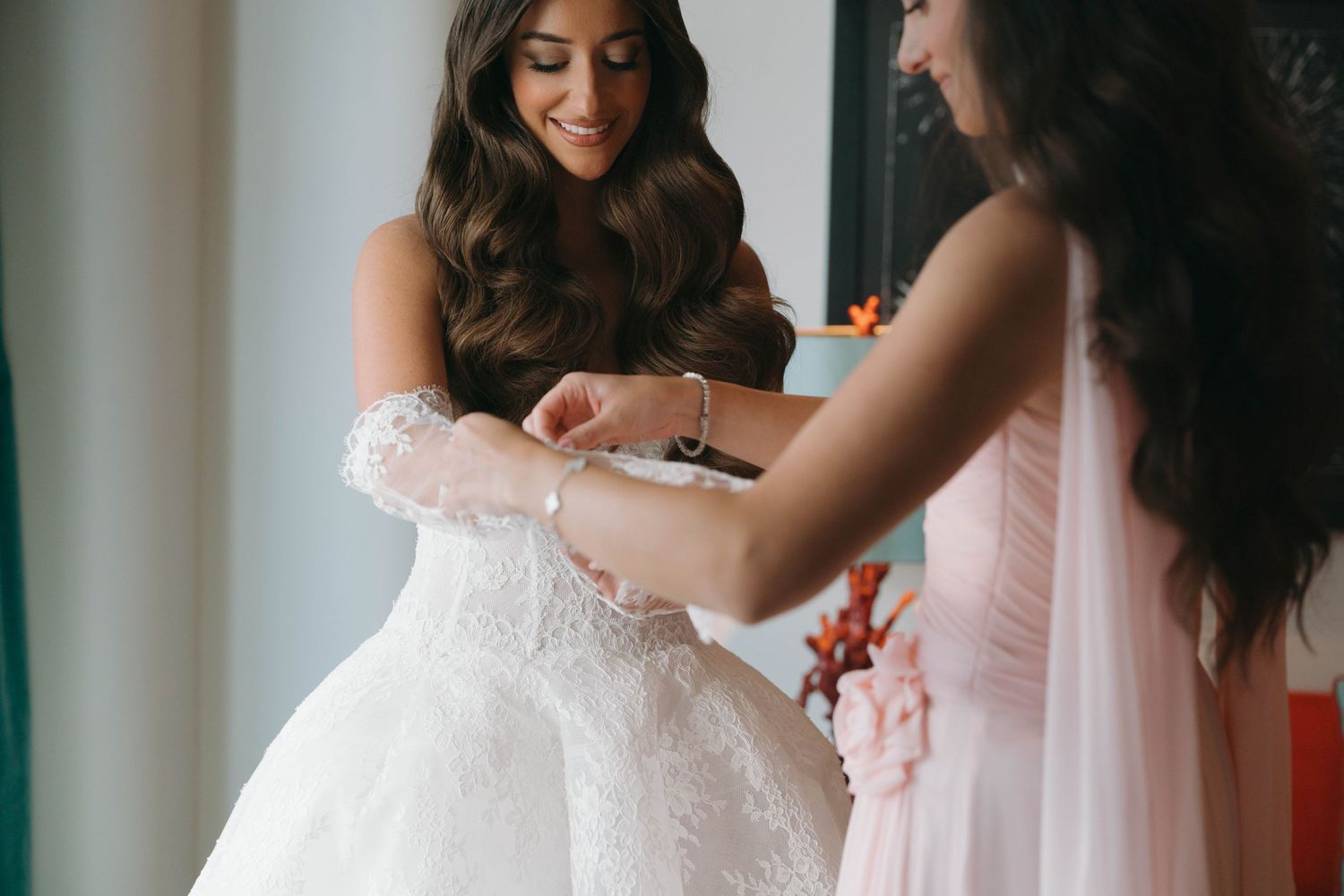 Person getting dressed in detailed white lace wedding gown.