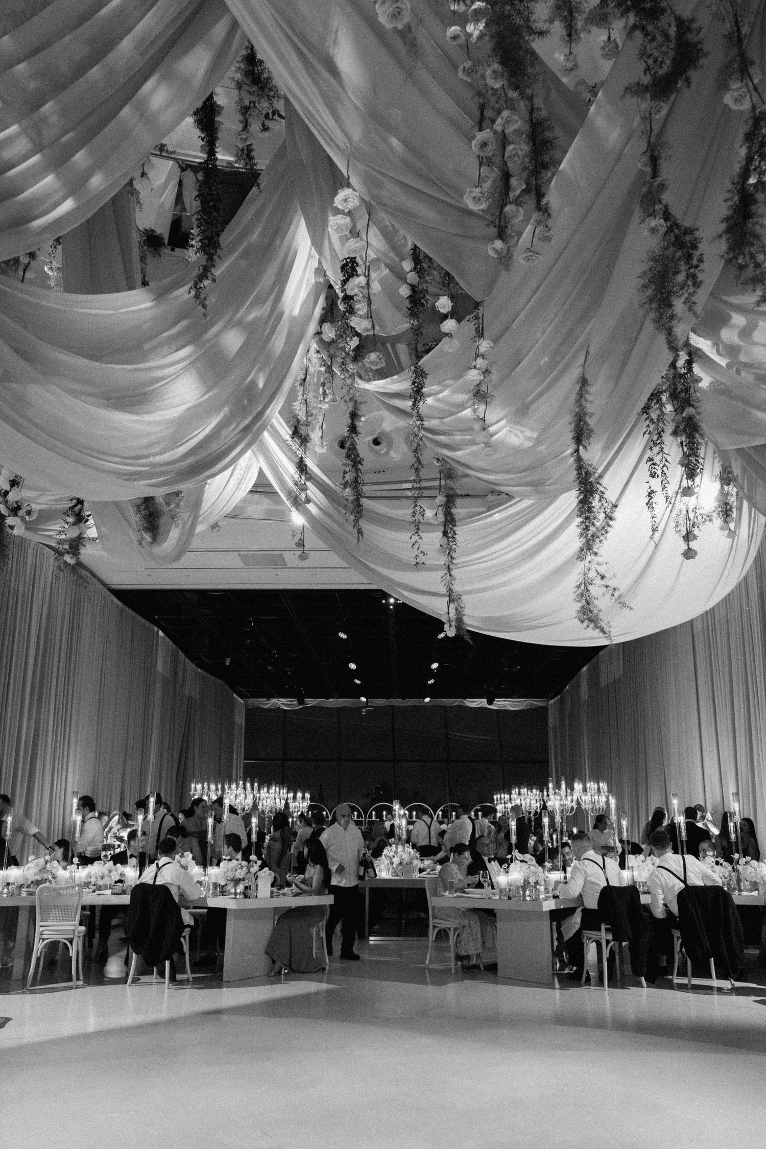 Elegant wedding venue with draped ceiling decor and floral arrangements.