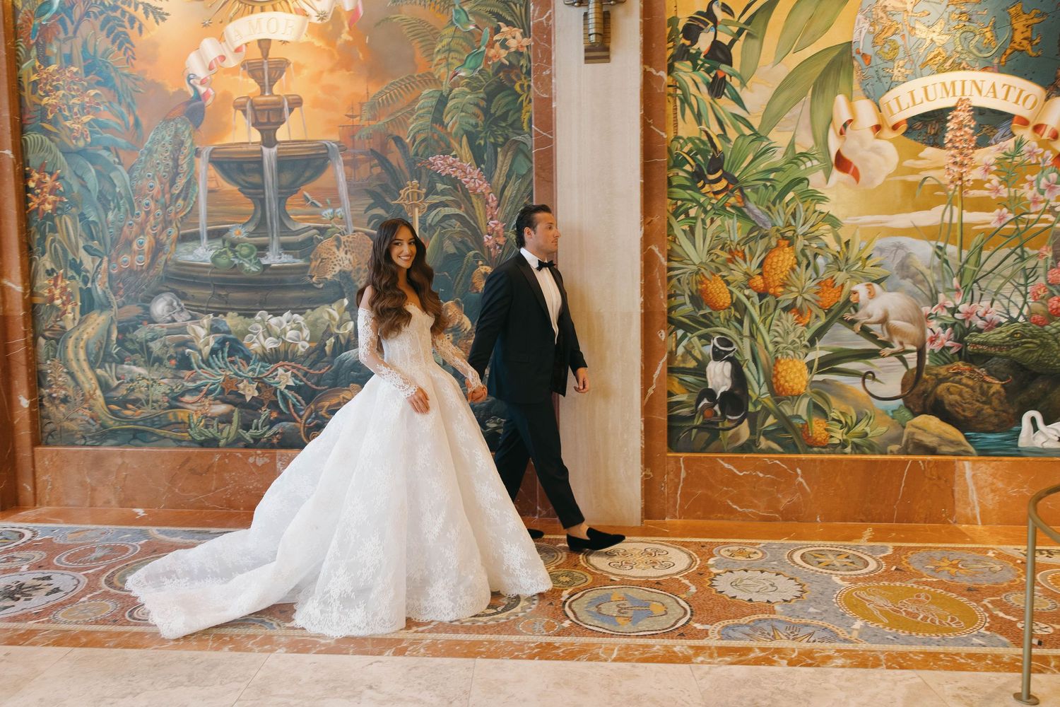 Wedding couple poses against colorful tropical murals in an ornate hallway.