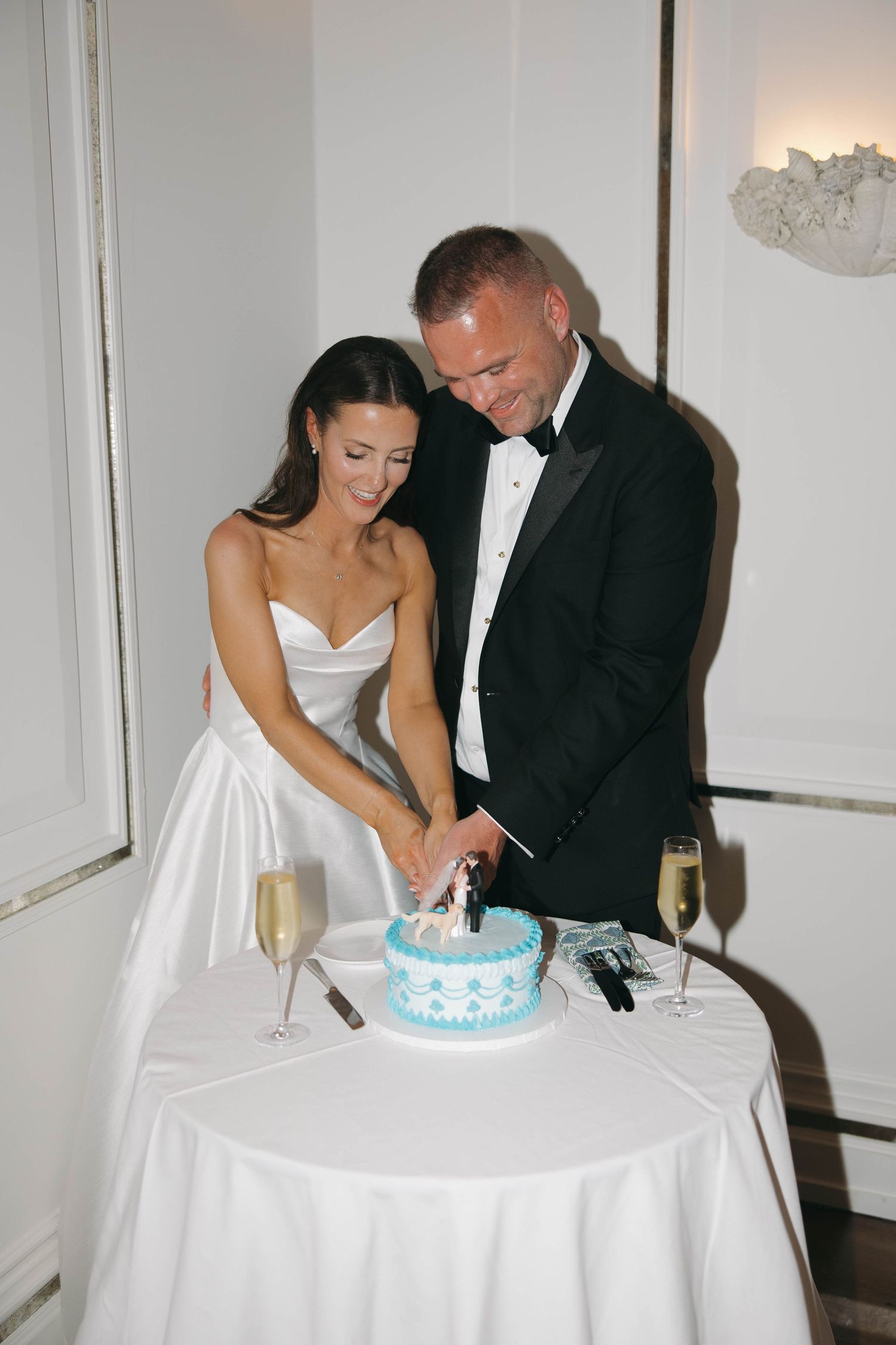 A couple cutting their blue and white wedding cake together at their reception.