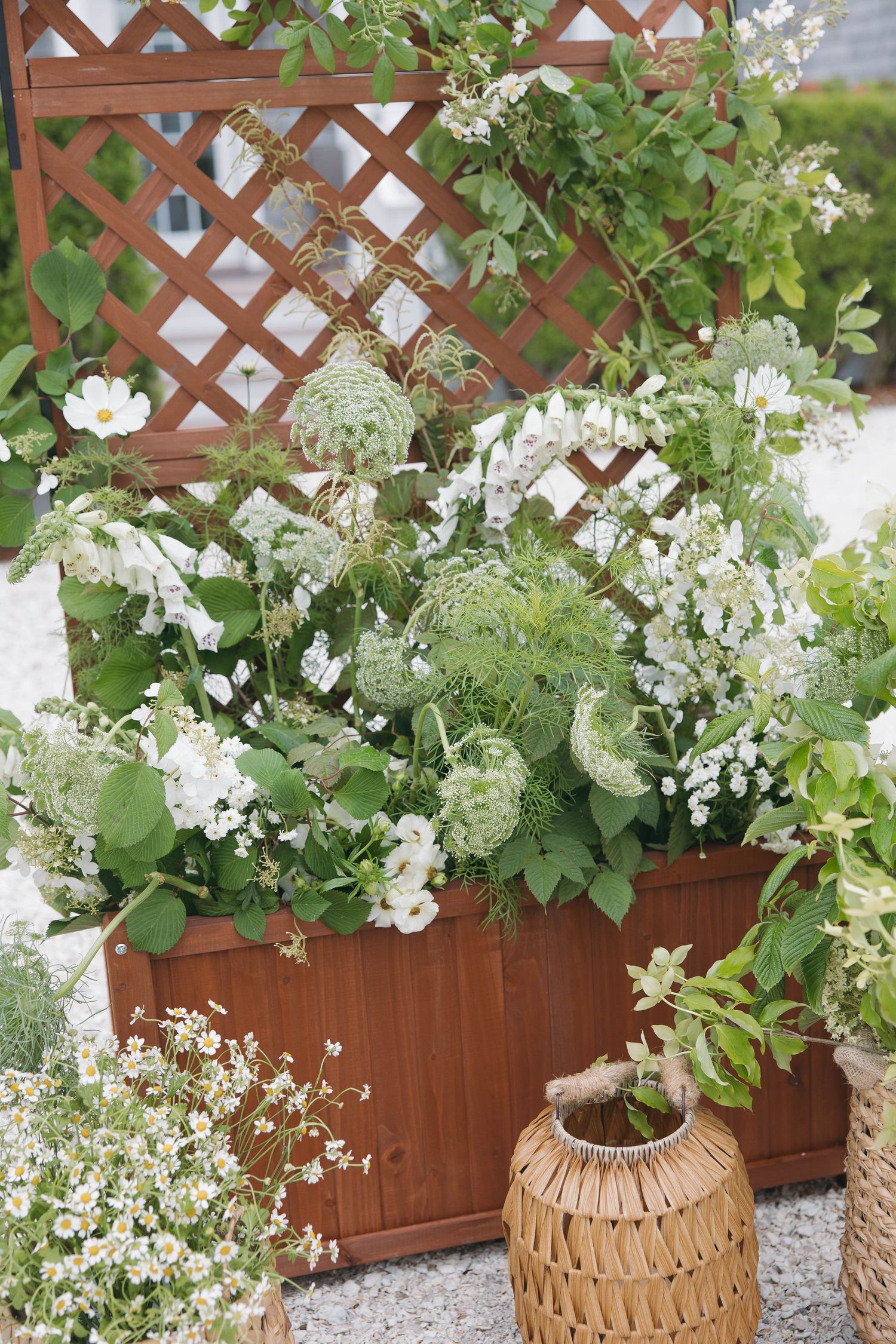 Lush white floral arrangements in woven baskets against wooden lattice backdrop.