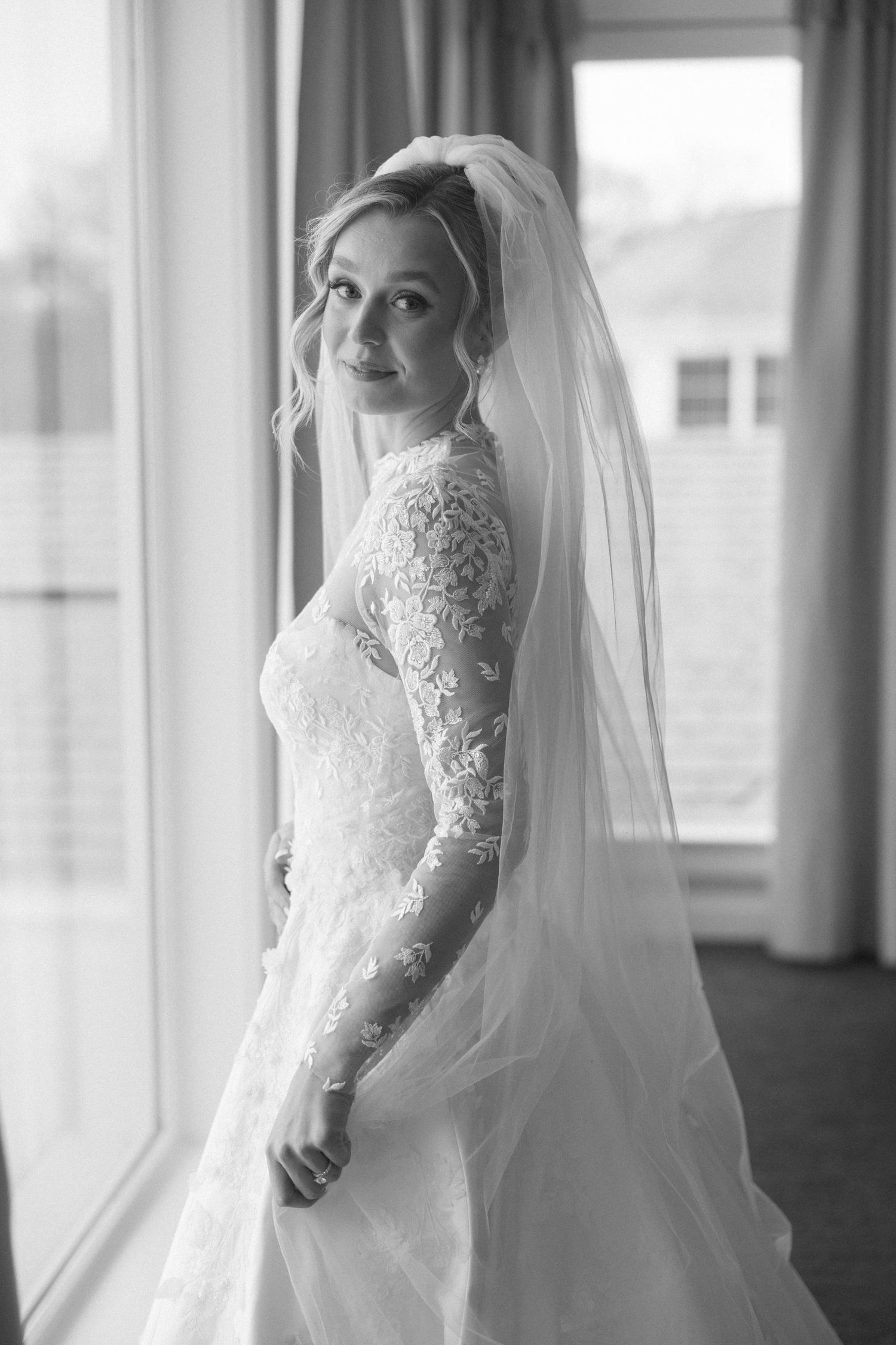 Elegant bridal portrait showcasing intricate lace details against window backdrop.